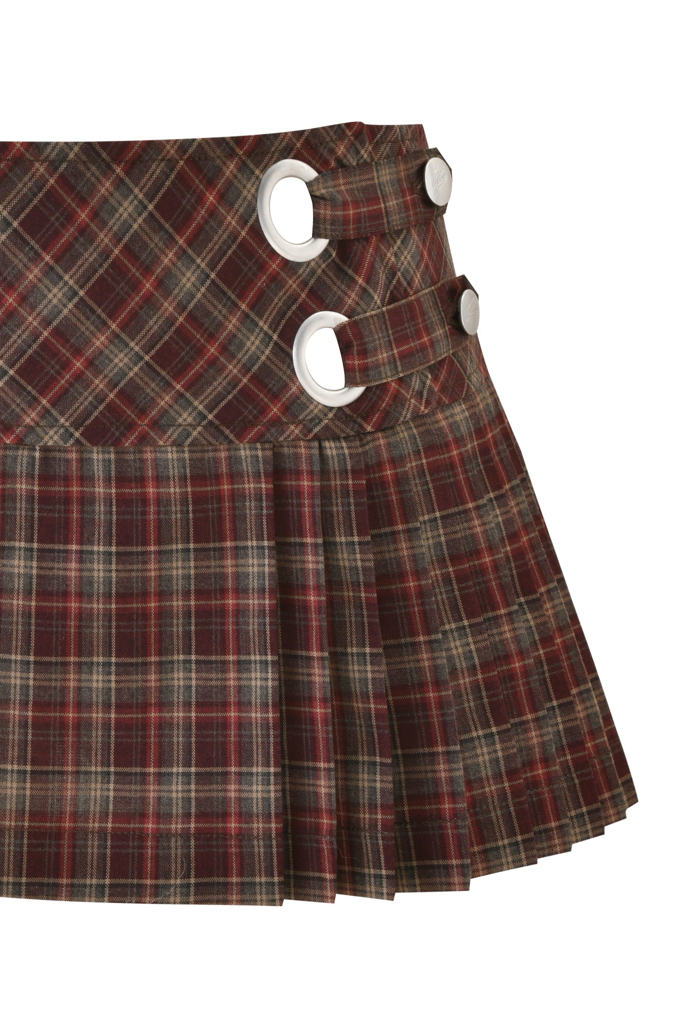 The ROUX MINI SKORT - BURGUNDY PLAID by I.AM.GIA is a low-rise mini skort in brown and red plaid, featuring pleats and two horizontal straps with large silver grommets and buttons on the waistband.