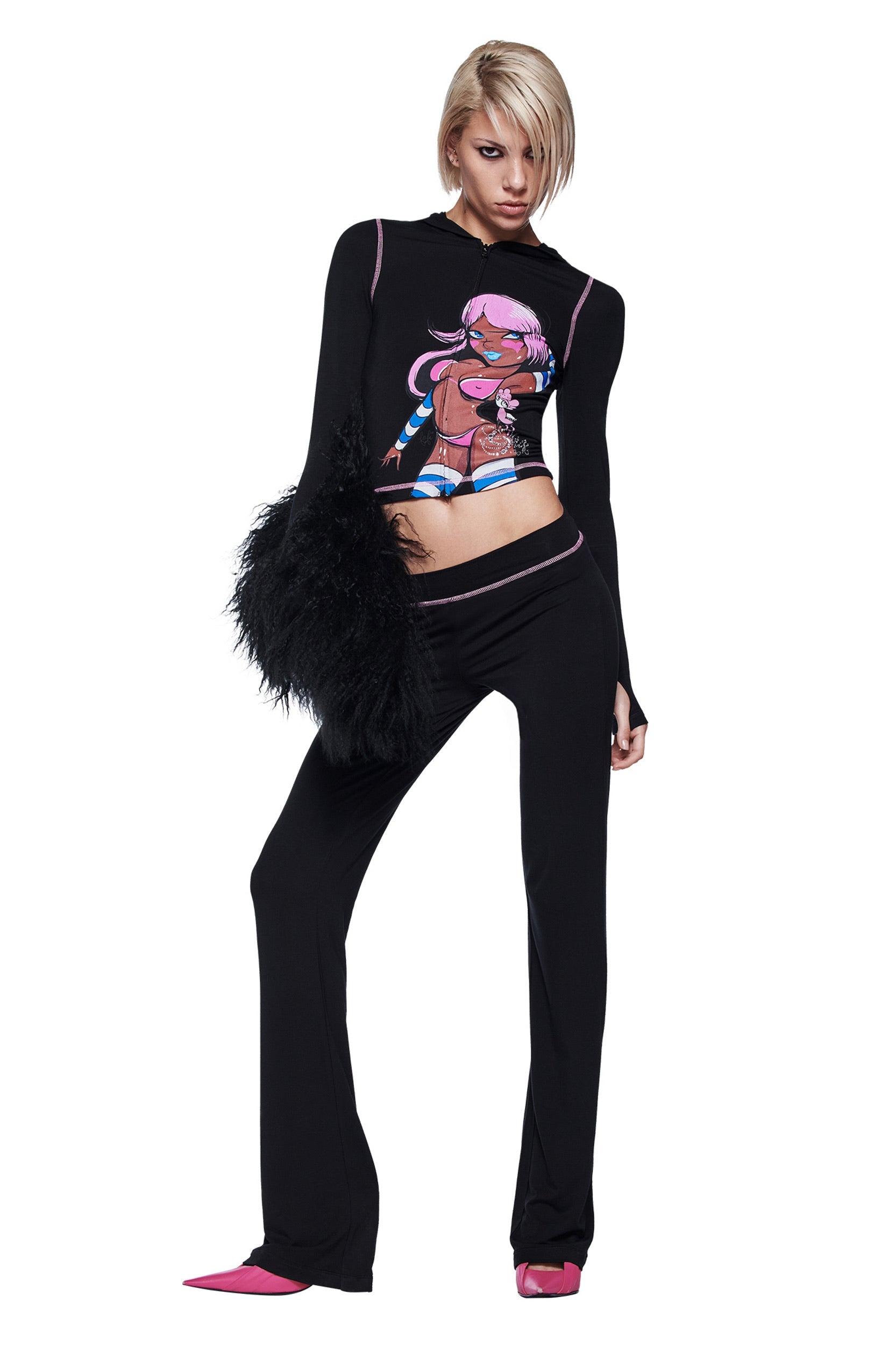 A person poses confidently against a white background in the I.AM.GIA FAFI BLARE HOODIE - BLACK with diamanté detailing, flared pants, pink heels, and a fluffy black bag.