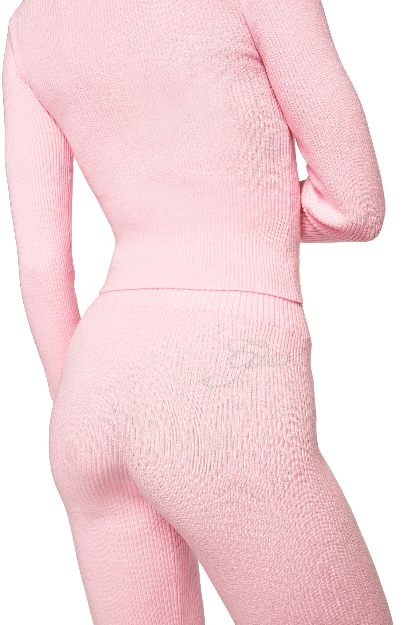 A person is seen from behind, arms slightly bent, wearing a fitted ribbed pink top with I.AM.GIA's BLARE KNIT TRACKPANT in pink.