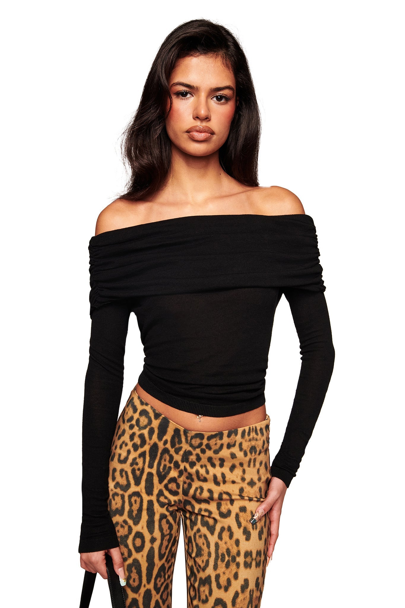 A woman with long dark hair wears the I.AM.GIA VEYRA LONG SLEEVE TOP in black, styled off the shoulder with a bodycon fit, paired with high-waisted leopard print pants against a white background.
