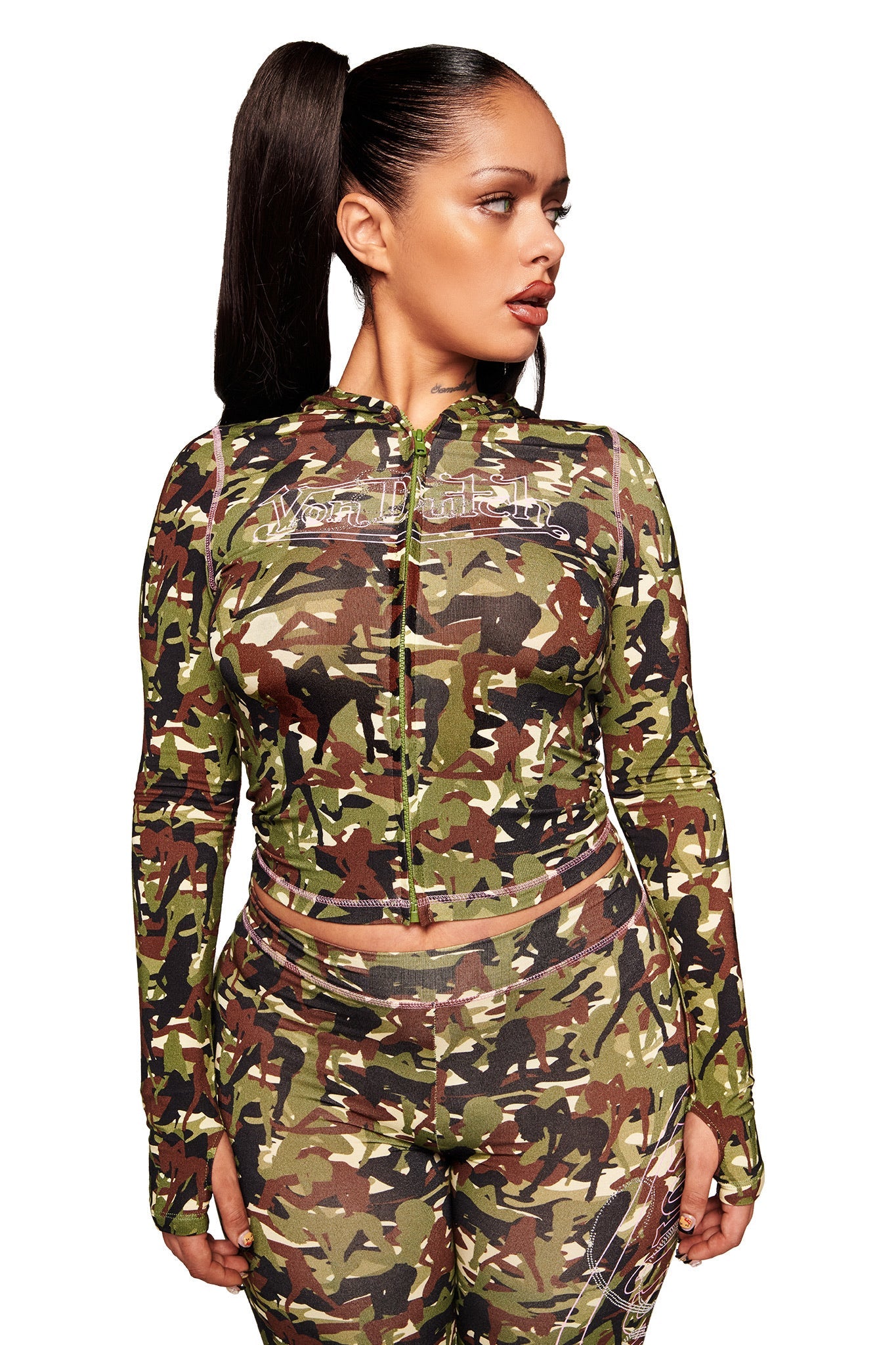 A woman with a high ponytail wears the I.AM.GIA X VON DUTCH BLARE HOODIE in GIA GIRL CAMO, facing slightly left against a plain white background.