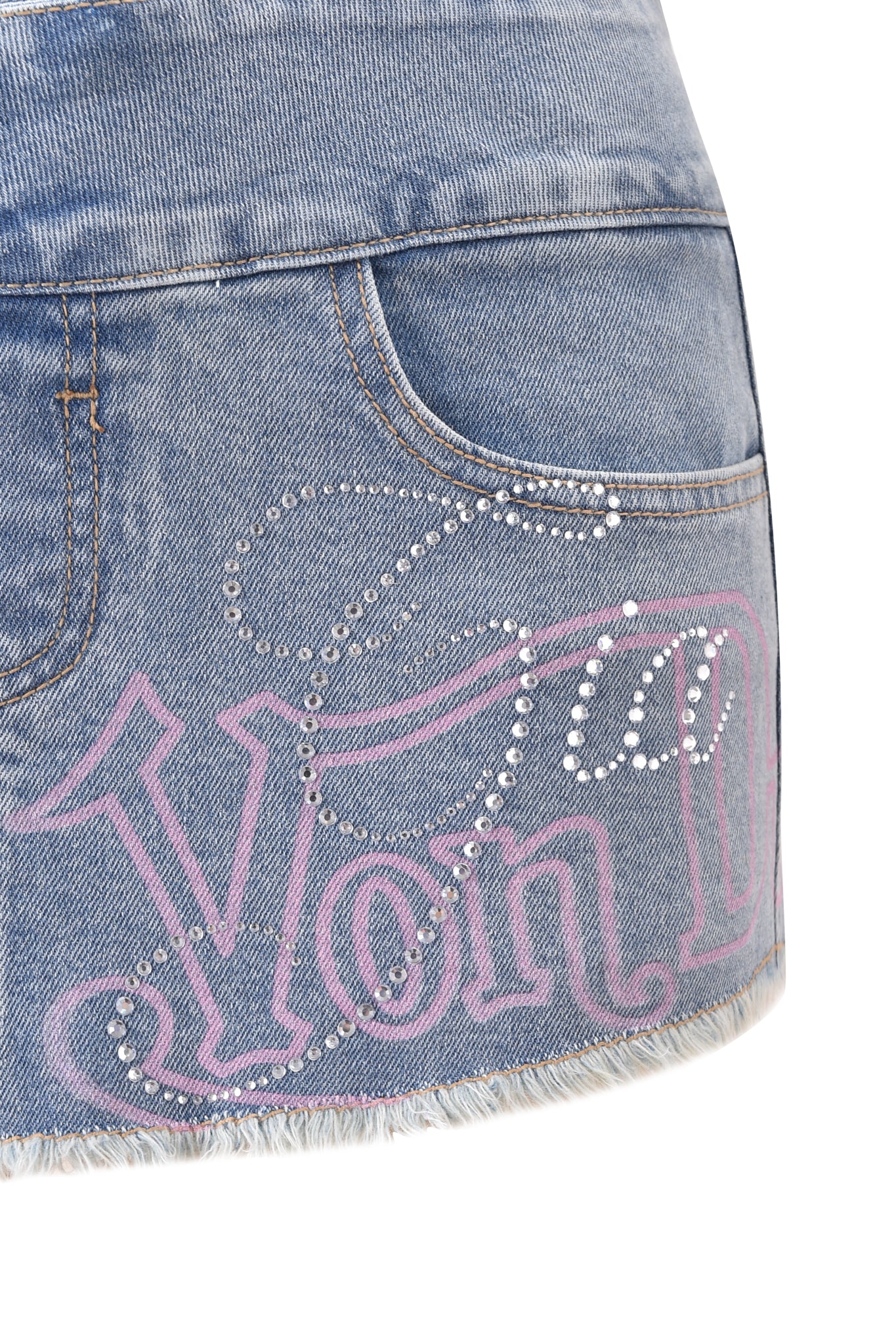 Close-up of the I.AM.GIA X VON DUTCH SYNDRA DENIM MINI SKORT in light wash, featuring a frayed hem, pink outlined "Von Dutch" text, and rhinestone details on the front pocket—a special collab by I.AM.GIA.