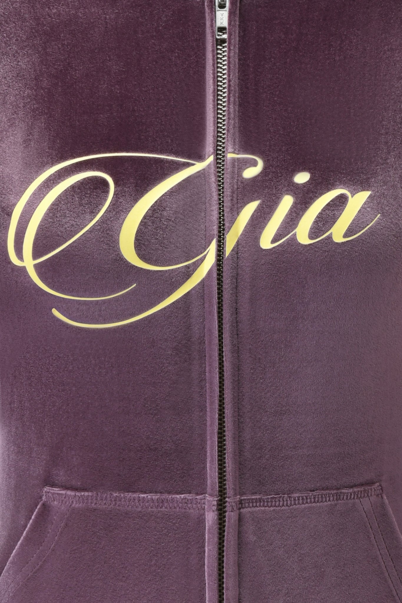 Close-up of the I.AM.GIA BLARE VELOUR POCKET HOODIE in purple, showing a zipper running through the chest where GIA is scripted in large, yellow cursive letters.