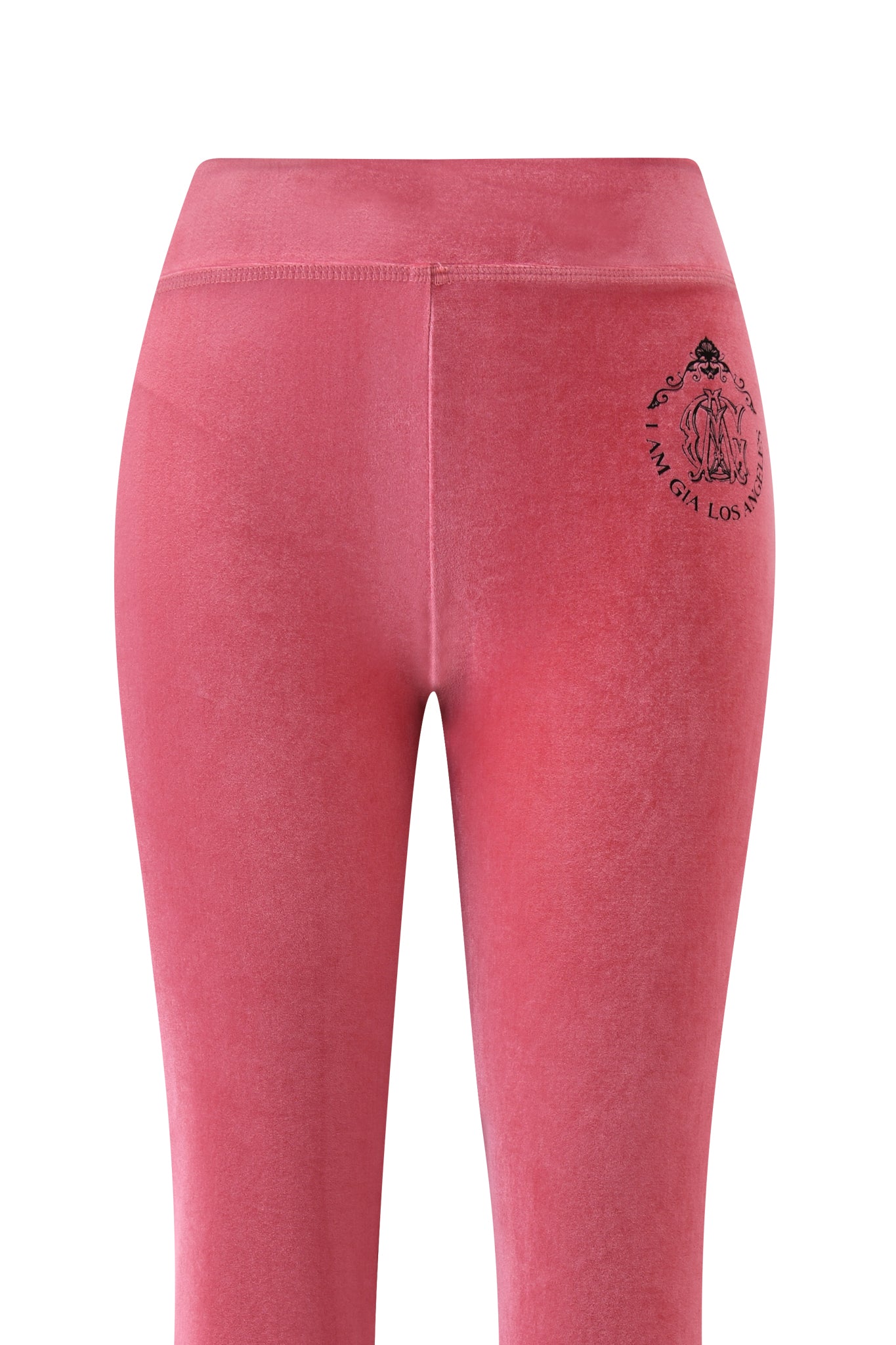 The I.AM.GIA BLARE VELOUR POCKET TRACKPANT in pink is shown from the back, featuring a small black graphic and text logo near the waistband on the right side. The high waistband and velour fabric offer a sculpted fit.