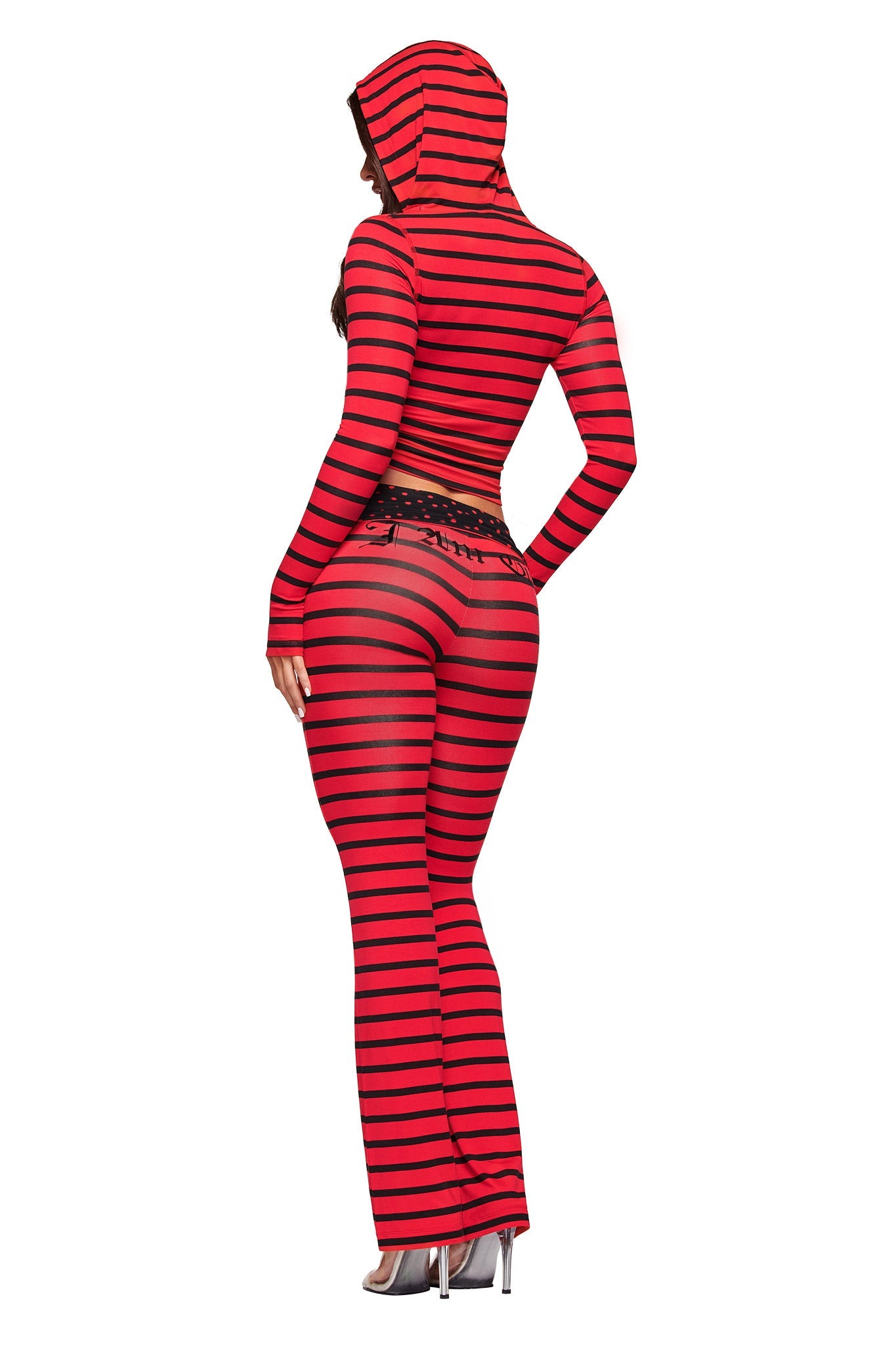 A person wearing the I.AM.GIA BLARE FOLDOVER TRACKPANT in red and black stripe with a matching hooded crop top and high heels stands with their back to the camera against a white background.