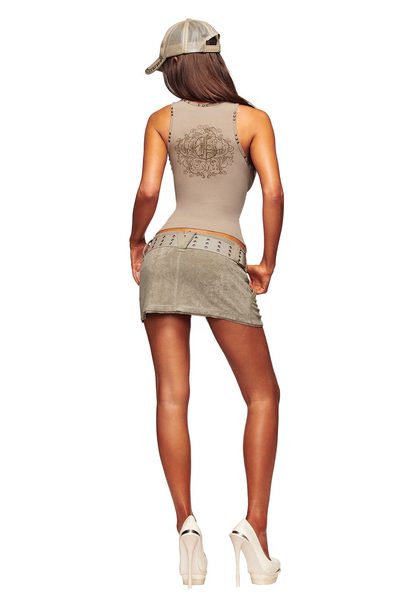 A woman stands with her back to the camera against a white background, wearing the I.AM.GIA ISSHA TERRY MINI SKIRT in Stone, paired with a beige tank top, high heels, and a backwards cap.