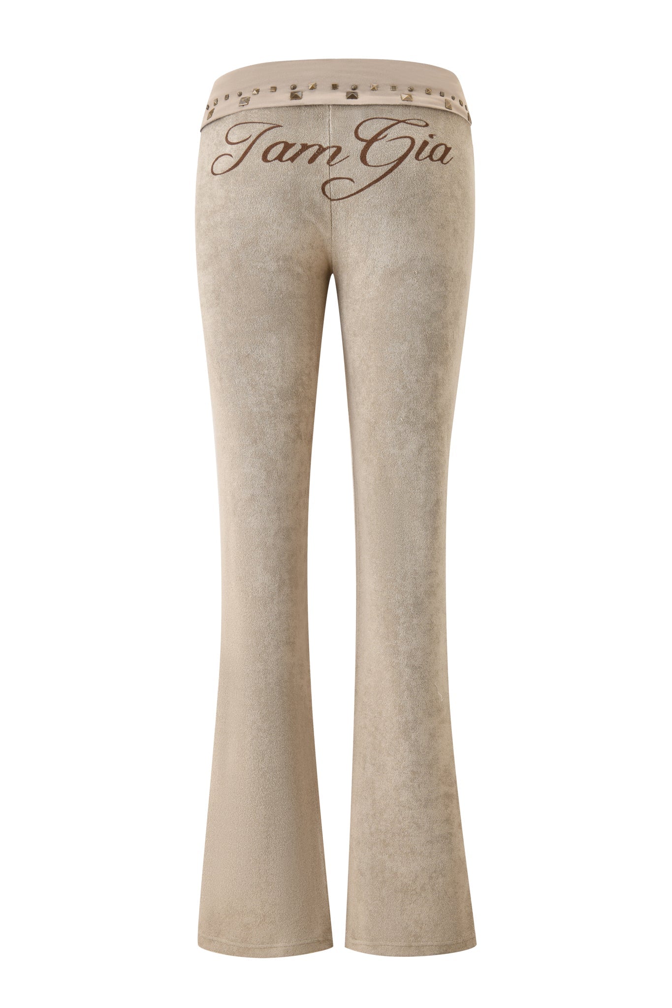 The BLARE STUDDED TERRY PANT - STONE by I.AM.GIA features beige flared legs, decorative studs on the waistband, and bold "TamGia" embroidery at the back—an elevated take on classic trackpants.