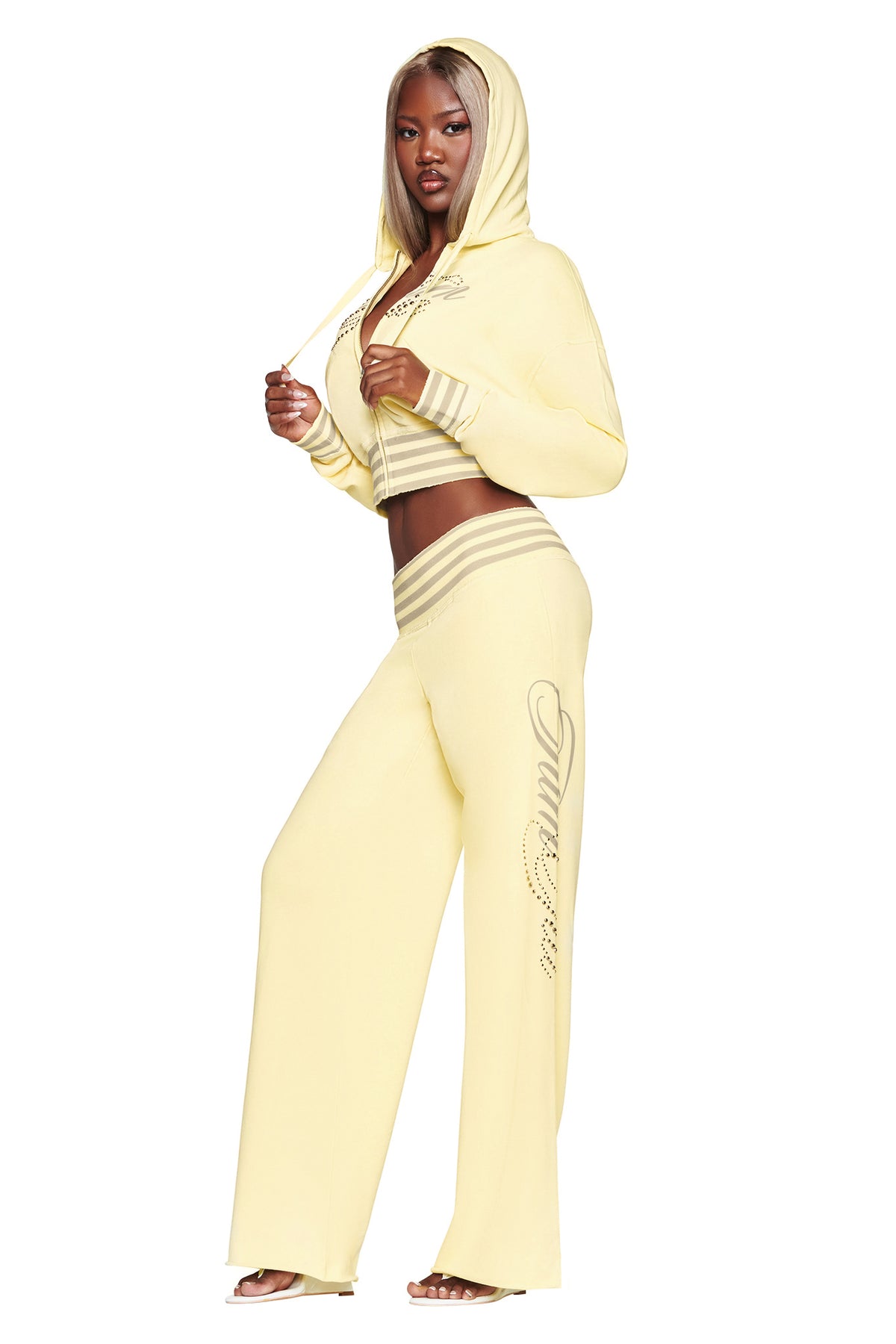A person wearing the VEDA JACKET - YELLOW by I.AM.GIA and matching wide-leg pants with silver writing stands confidently, looking forward against a white background.