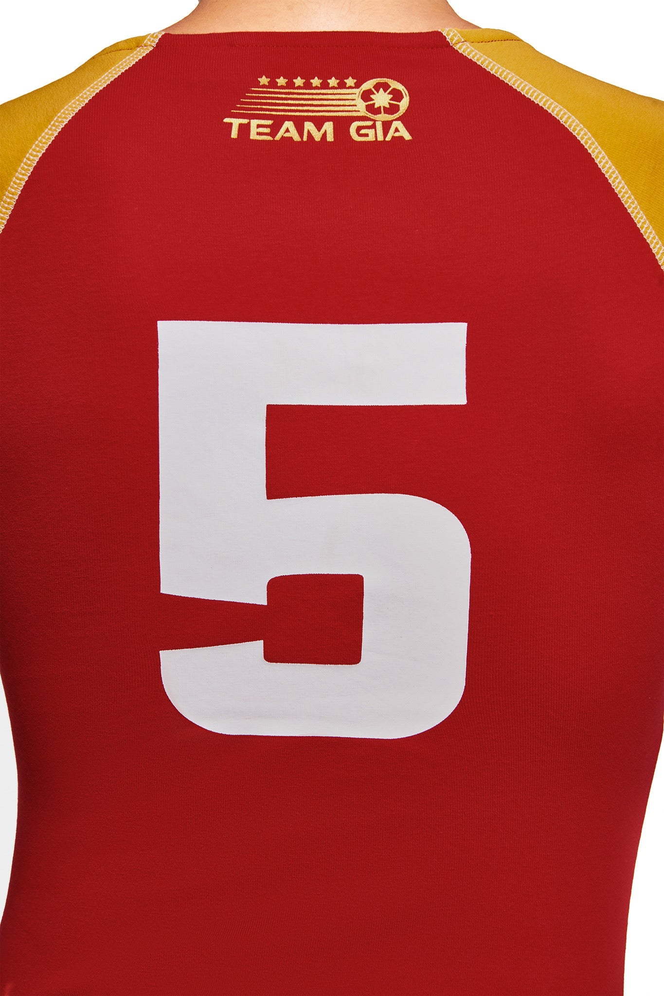 The back of the NOVIA LACE-UP T-SHIRT AND HEADBAND in red by I.AM.GIA features yellow accents, a bold white number 5, "TEAM GIA" lettering, and a star with clover emblem, inspired by iconic I.AM.GIA baby tee styles.