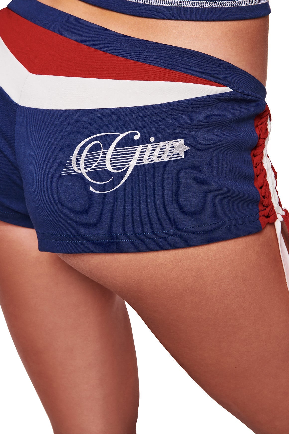 Close-up of lower torso and upper thigh wearing the I.AM.GIA NOVIA MICRO SPORT SHORT - NAVY, featuring blue low-rise design, red and white stripes, lace-up sides, and "Gigi" script.