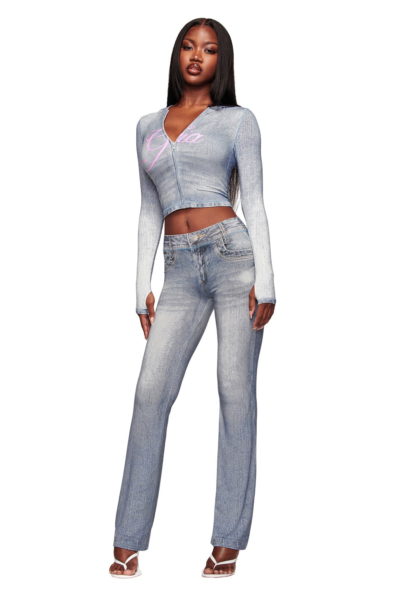 A woman poses confidently in I.AM.GIA’s BLARE TRACKPANT - DENIM TROMPE L'OEIL and a matching light blue crop top, styled with long straight hair and open-toe heels against a plain white background.