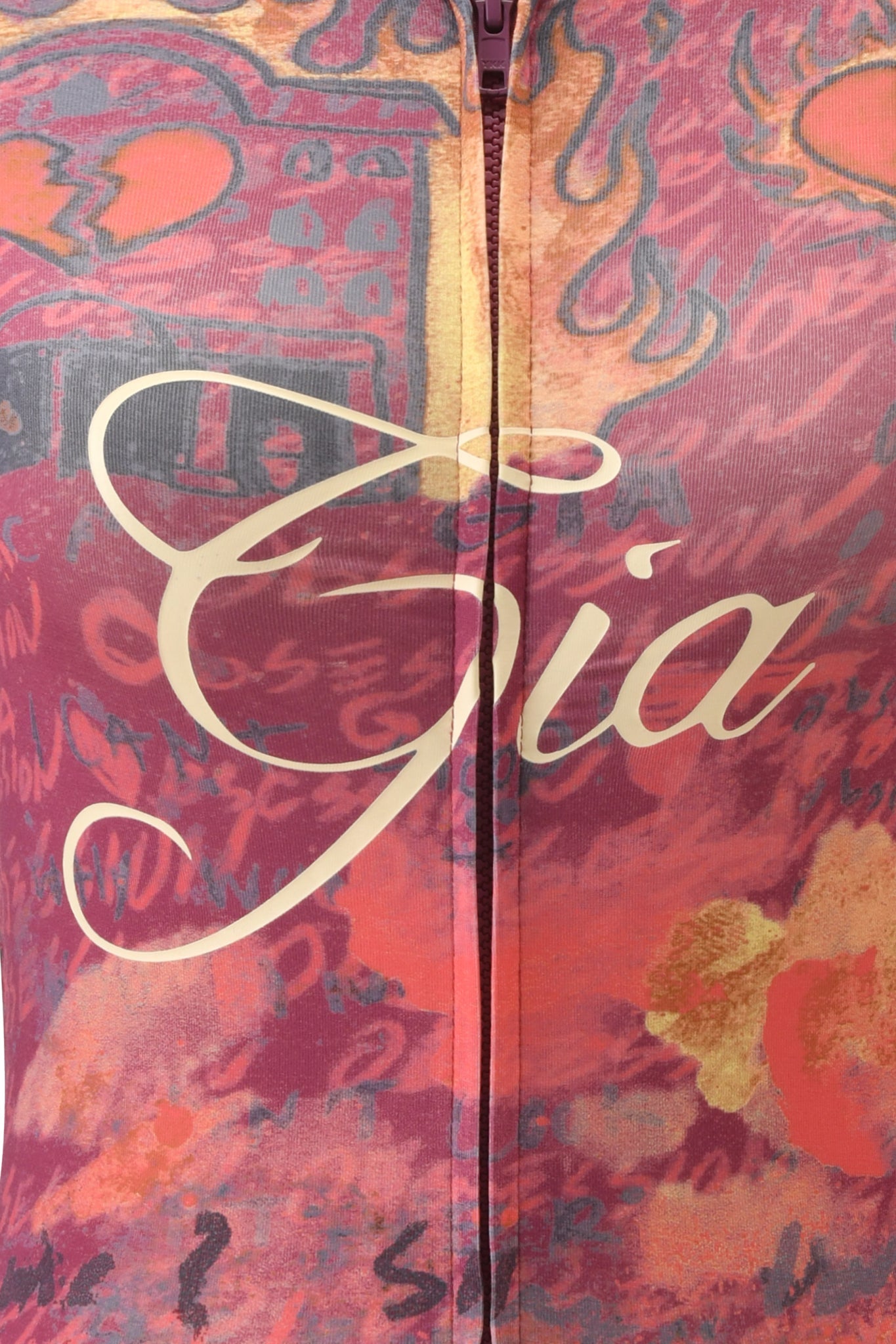 Close-up of fabric featuring an abstract, colorful pattern in red and orange hues with the words "T-REX BLARE" written across the center in elegant, cream-colored script, reminiscent of the signature style found on an I.AM.GIA hoodie.