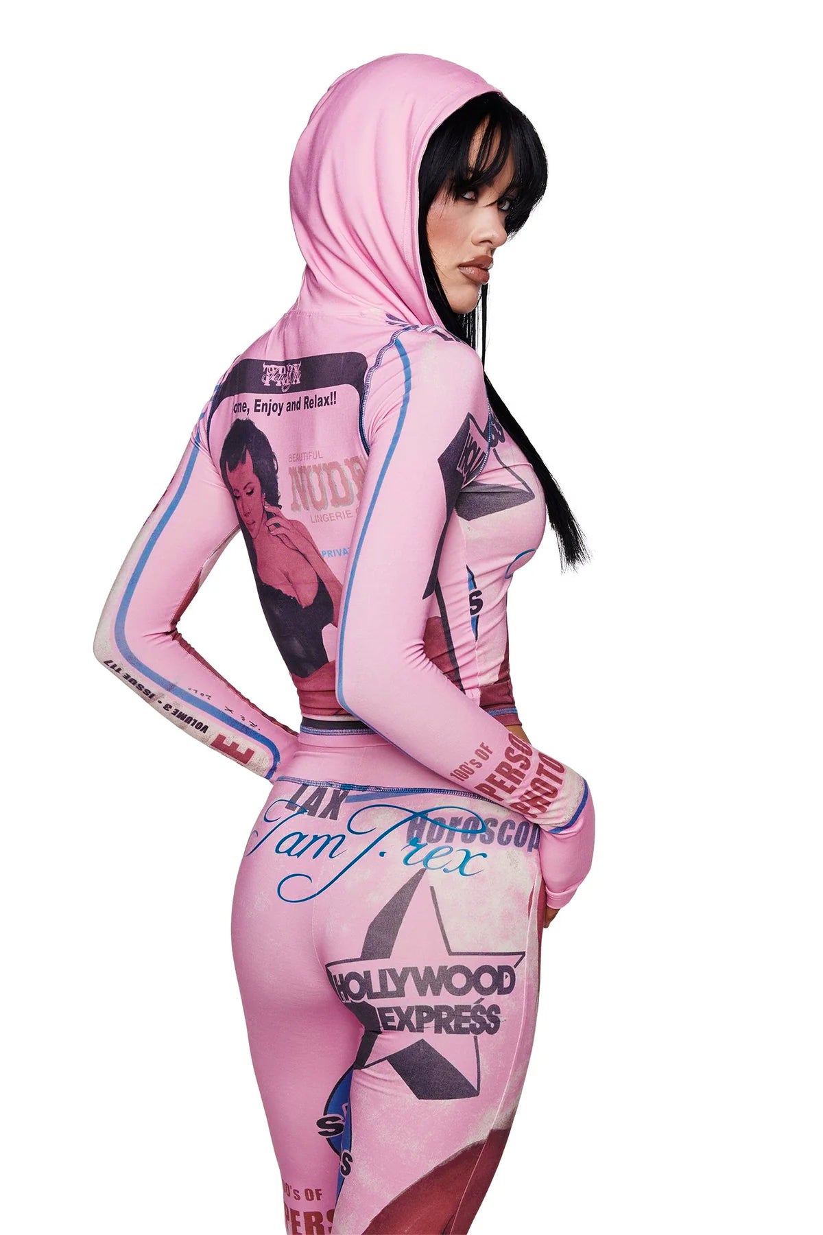 A woman poses with her body turned to the side and her head looking over her shoulder while wearing the I.AM.GIA T-REX BLARE HOODIE in pink, a form-fitting bodysuit crafted from bamboo fabrication and adorned with vintage-inspired graphic prints and text.