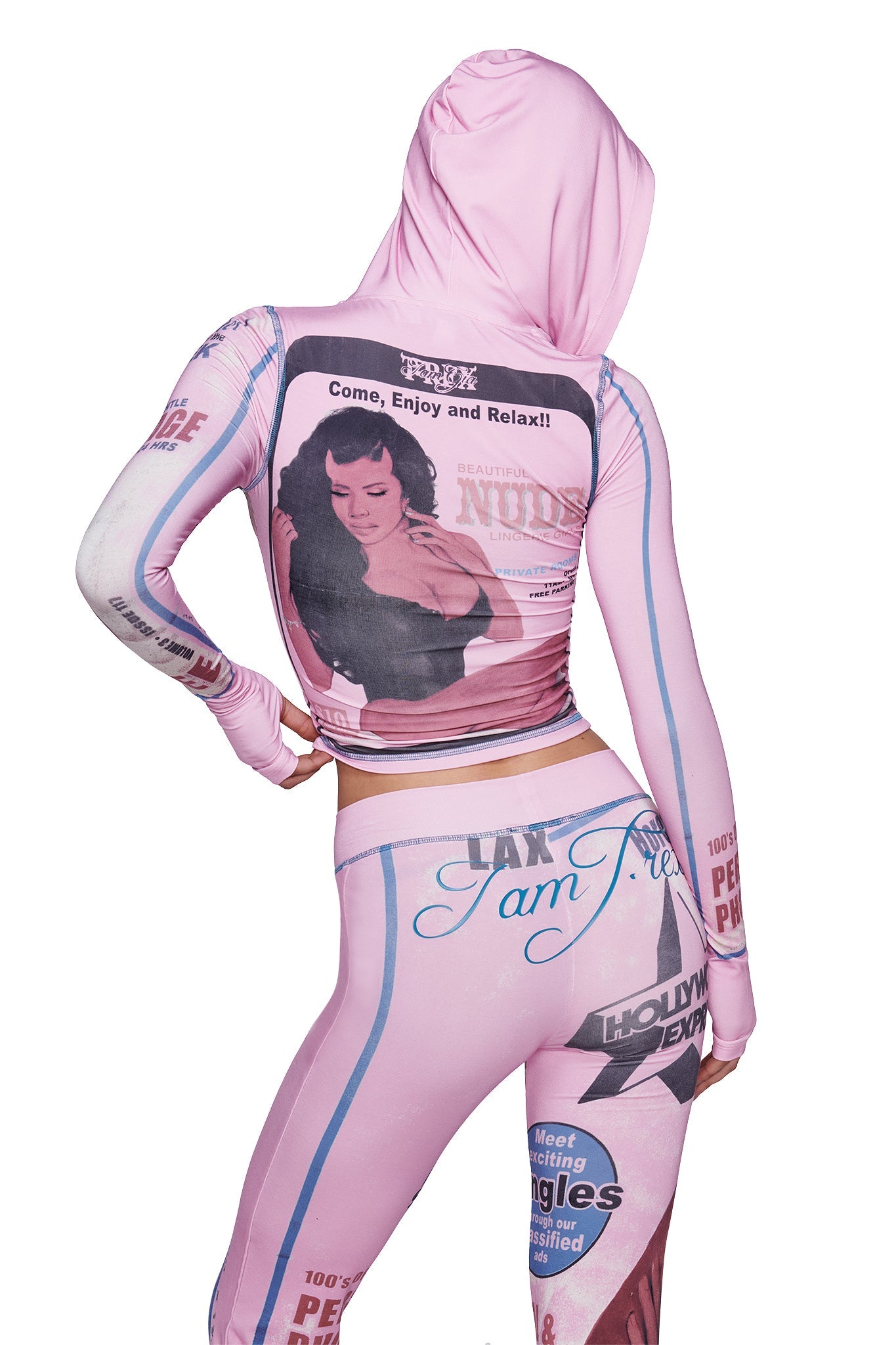 A person is seen from behind wearing the I.AM.GIA T-REX BLARE HOODIE in pink, which features a vintage-inspired print with a black-and-white photo of a woman, retro advertisement graphics, and the text “Come, Enjoy and Relax!!”.