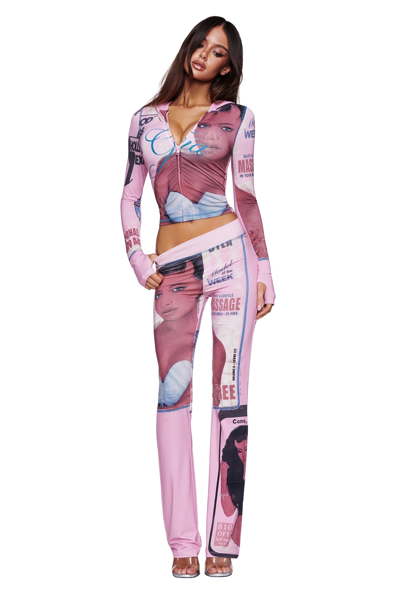 A woman stands against a plain white background wearing the I.AM.GIA T-REX BLARE HOODIE in pink, which features a fitted silhouette adorned with assorted magazine cover prints and images of faces.