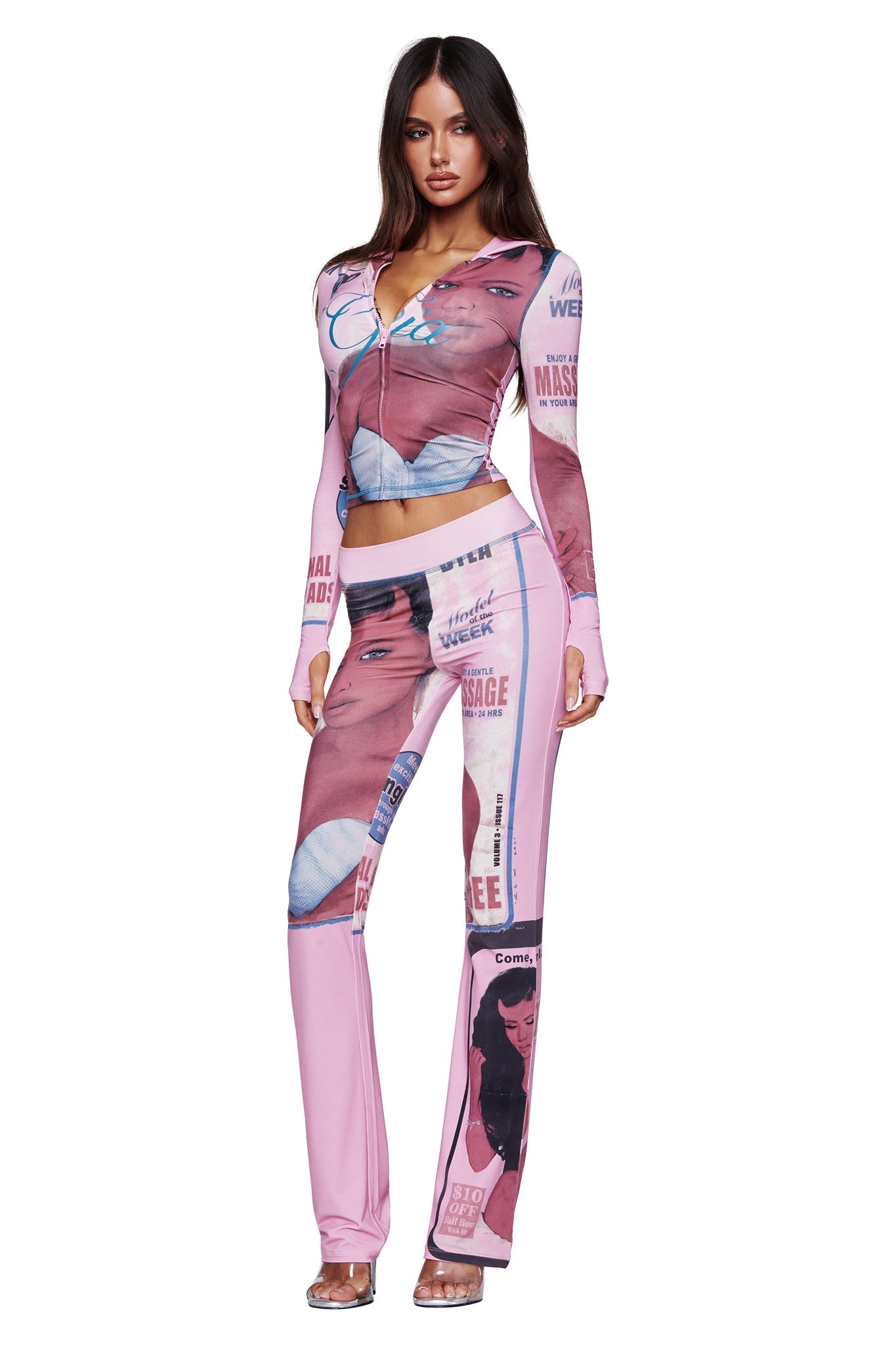 A woman poses against a white background wearing the T-REX BLARE TRACKPANT in pink by I.AM.GIA—a matching set featuring a zip-up top and flared lounge pants adorned with various retro magazine-style images and text.