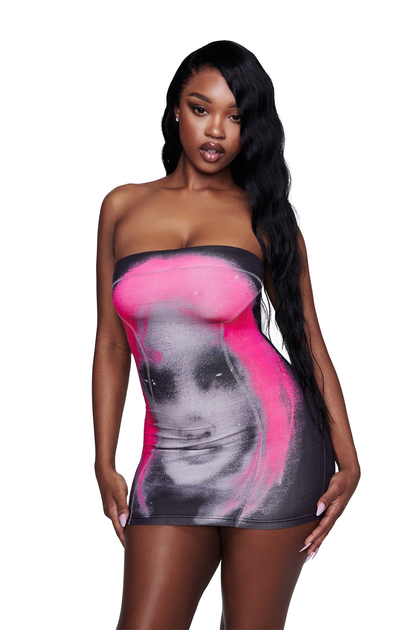 A woman with long wavy black hair wears the I.AM.GIA T-REX BLARE BOOB TUBE MINI DRESS in black, a strapless bodycon mini dress featuring a bold pink and black graphic face print. The background is plain white.