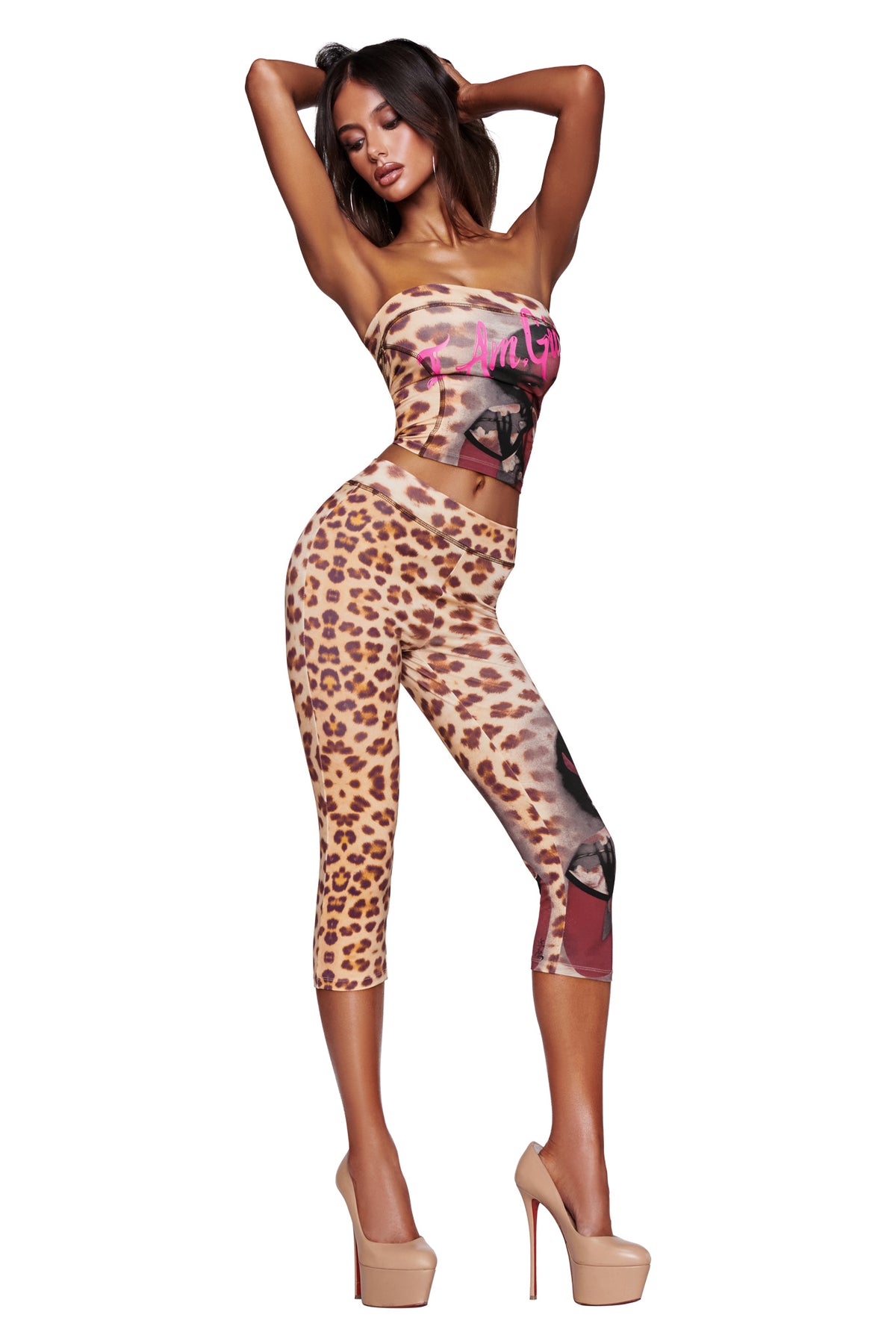 A woman with long hair poses in high heels against a white background, wearing the I.AM.GIA T-REX BLARE BOOB TUBE - WILD CARD and matching graphic cheetah print capri leggings.