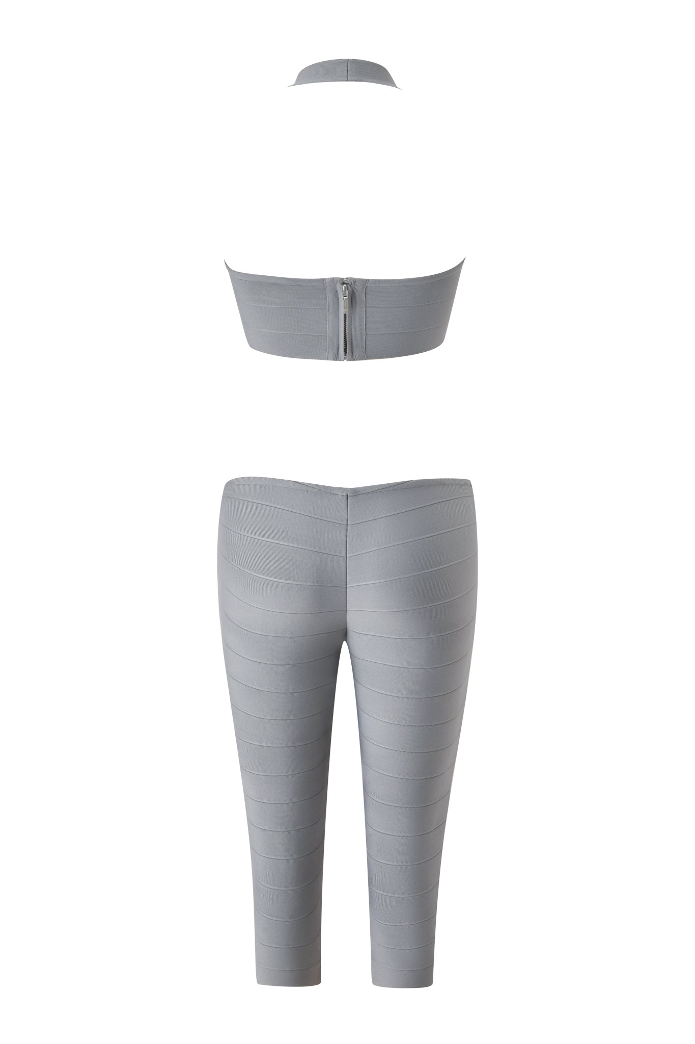 Back view of the EVA BANDAGE CAPRI JUMPSUIT in grey by I.AM.GIA, showcasing a sleek silhouette with a sleeveless halter crop top featuring a back zipper and matching high-waisted, fitted capri-length pants reminiscent of a gray bandage catsuit.