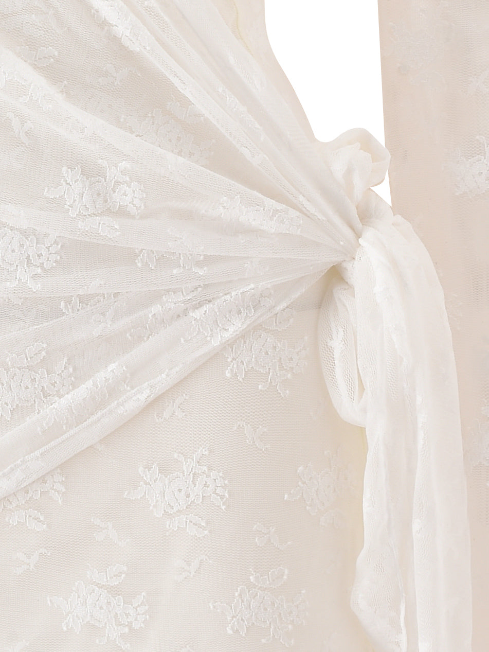 Close-up of cream lace fabric from the BONNY MINI DRESS by I.AM.GIA, featuring an intricate floral pattern tied in a soft knot with a draped effect. The detailed texture and delicate embroidery showcase the elegant, timeless appeal reminiscent of vintage-inspired design.