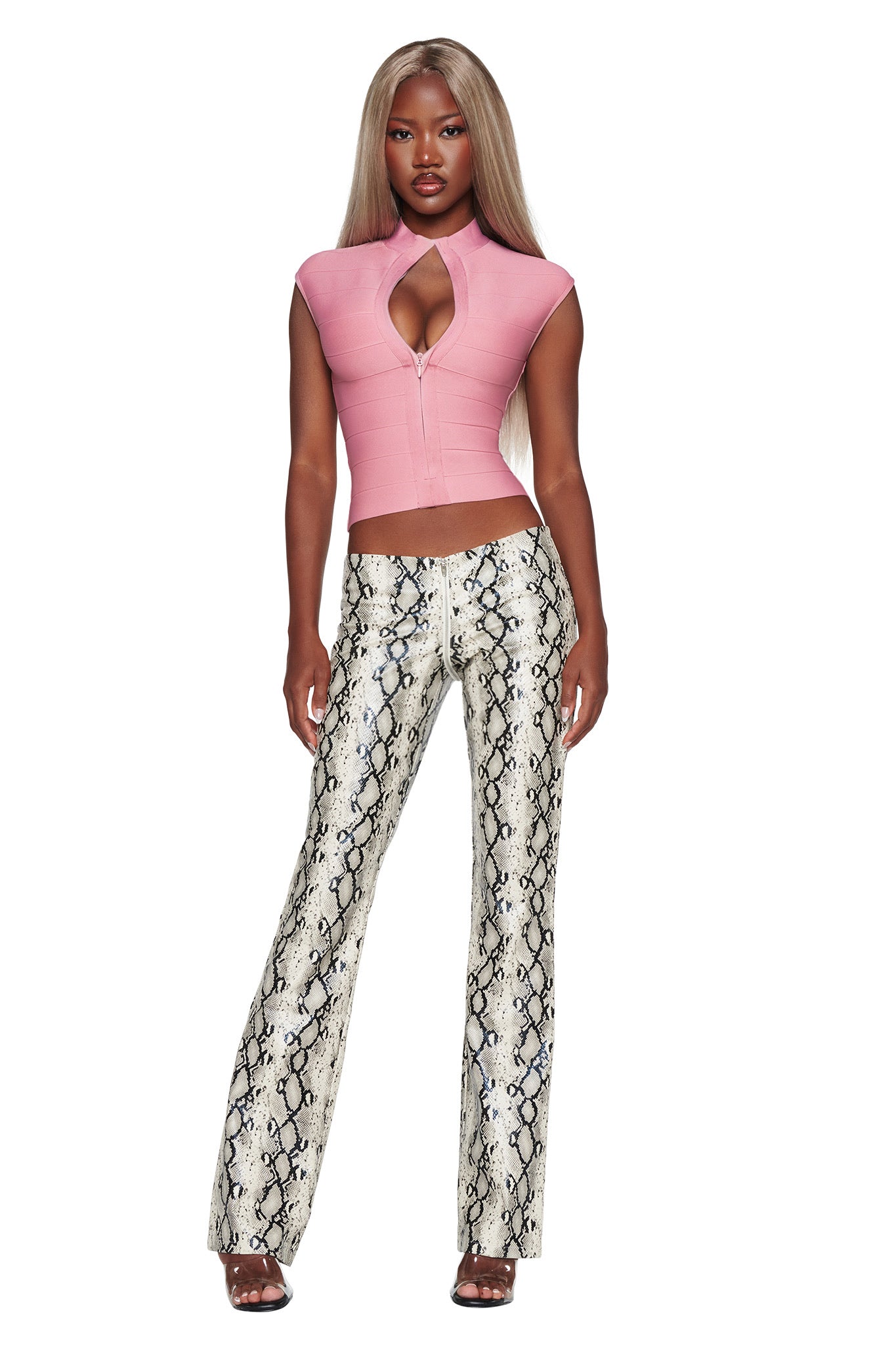 A woman stands facing forward, wearing a fitted pink top with a keyhole neckline and the I.AM.GIA HENDRIX 2.0 PANT in Cream Snake—a pair of high-waisted, straight-leg faux python leather pants. She has long, straight blonde hair and black high-heeled sandals, creating a chic night out look.