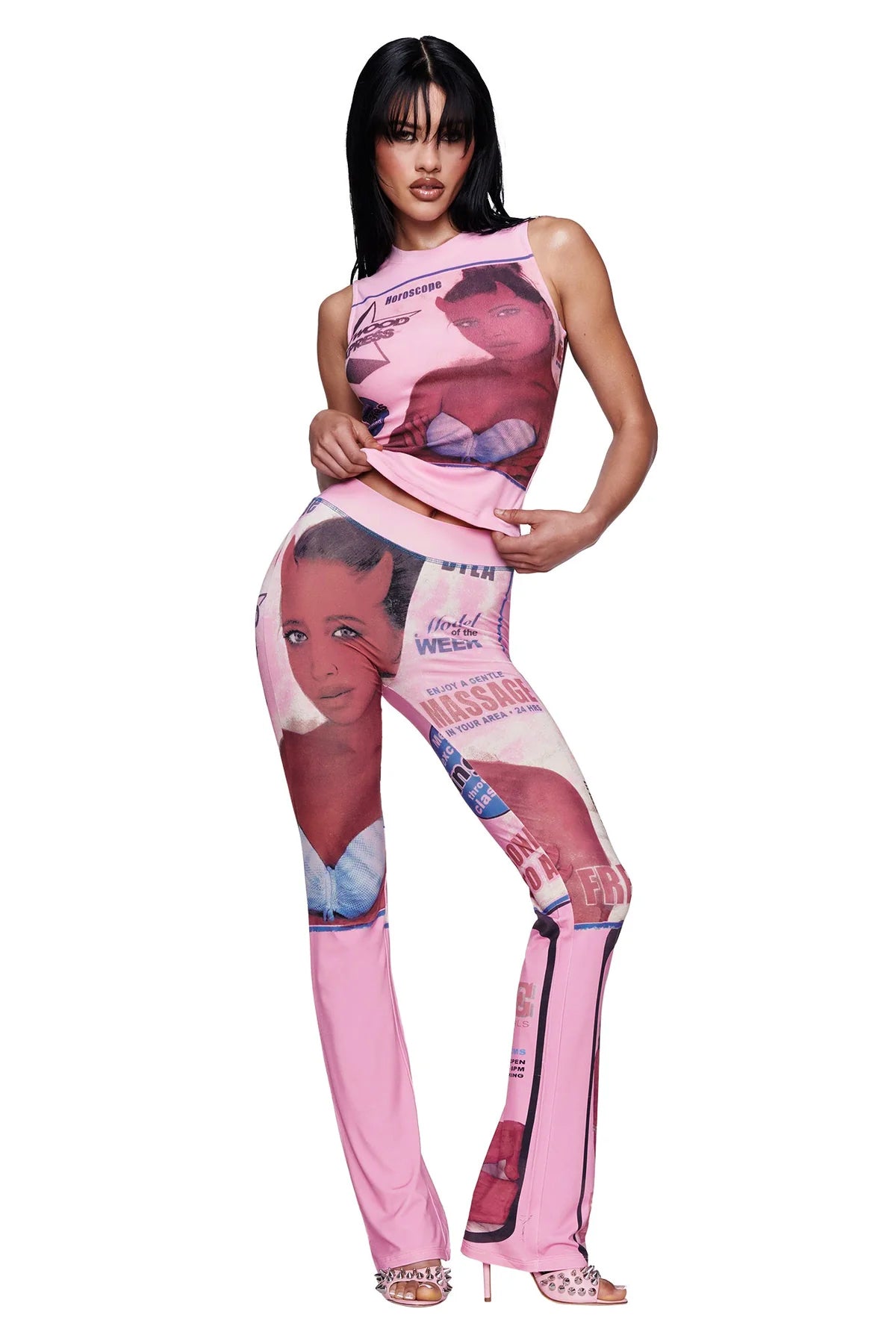 A woman poses against a white background wearing the I.AM.GIA T-REX COURTNEY TANK in pink, a baby pink muscle tank crafted from heavyweight cotton jersey and adorned with exclusive magazine-style placement print images and text, styled with matching pants.