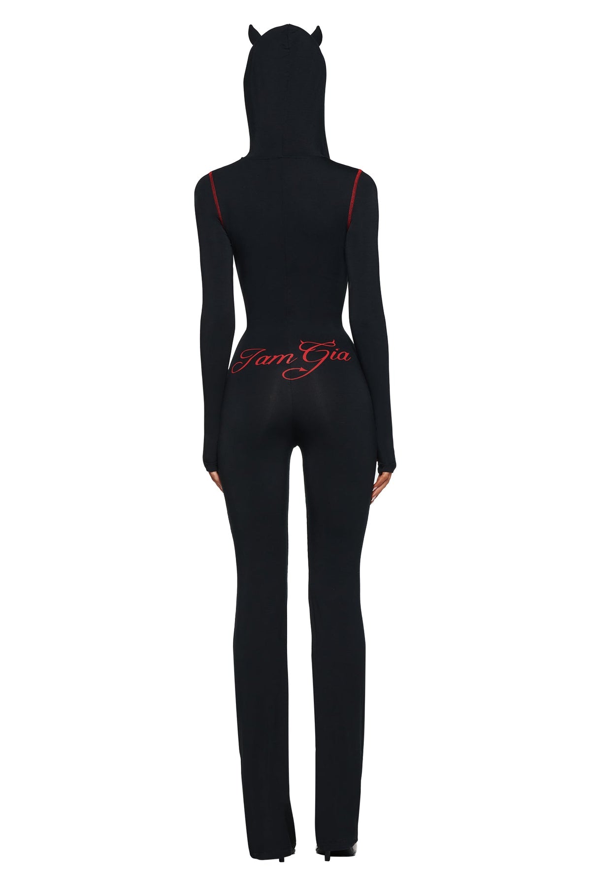 A person in the BLARE HORN JUMPSUIT - BLACK by I.AM.GIA, featuring a devil horn hood and red logo on the back, stands facing away against a white background.