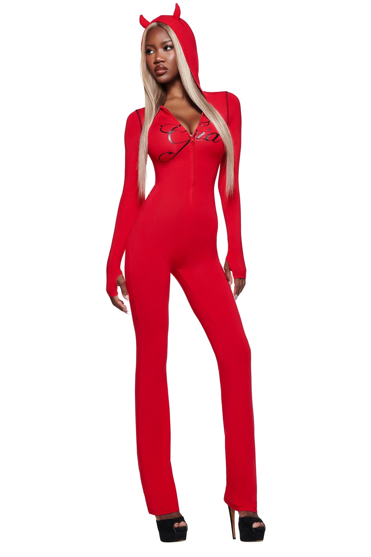 A woman in the I.AM.GIA BLARE HORN JUMPSUIT - RED with a devil horn hood poses confidently in black heels against a white background.