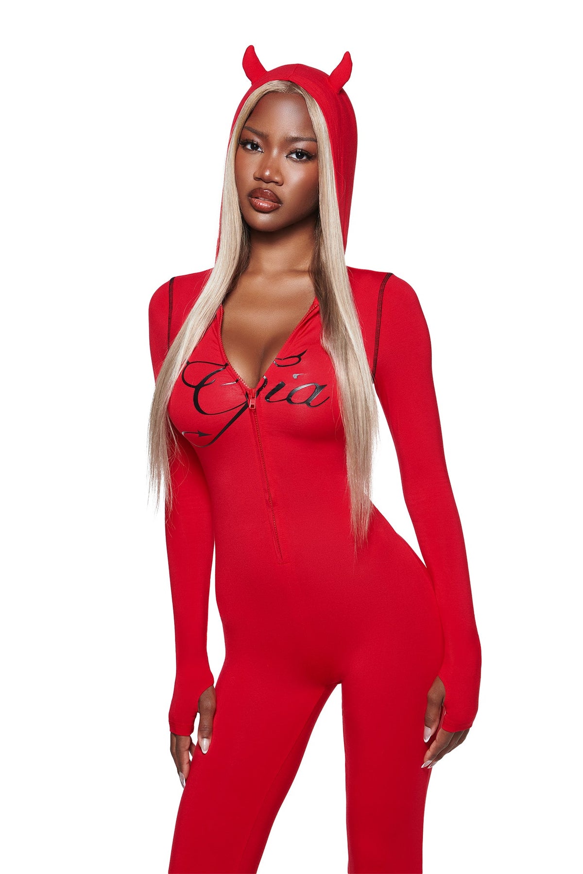 A woman with long straight blonde hair and a serious expression stands facing forward in the I.AM.GIA BLARE HORN JUMPSUIT - RED, featuring small devil horns and black script text on the chest.
