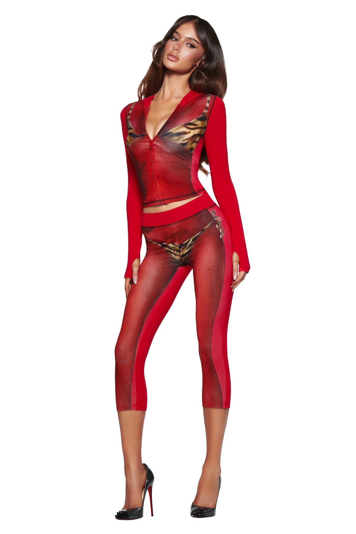 Woman in the T-REX SPRAY BODY BLARE HOODIE - RED by I.AM.GIA, featuring a fitted zip-front, illusion sheer panels, and an airbrushed bikini body print, posing in black heels against a white background.