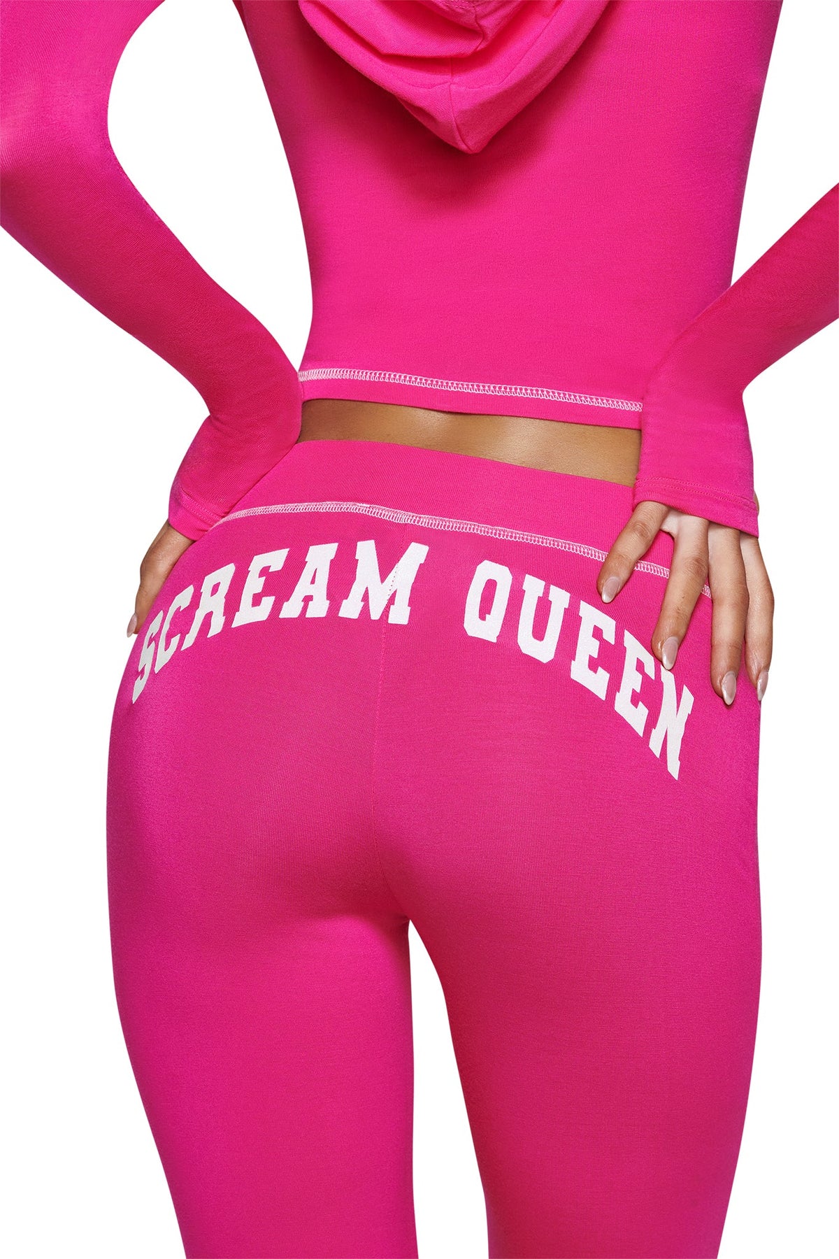 A person wearing the I.AM.GIA BLARE TRACKPANT - HOT PINK SCREAM QUEEN, which features the bold Scream Queen graphic printed in white on the back. Their hand rests on their hip, and the photo is cropped at the waist and mid-thigh.