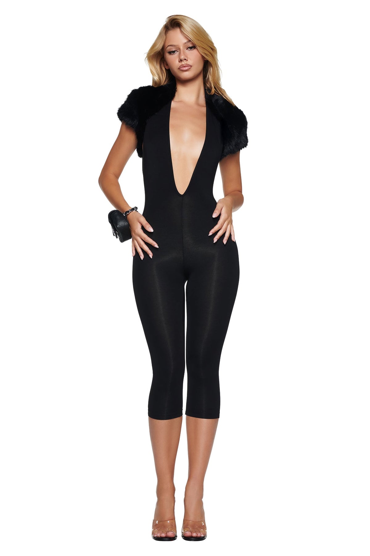 A person wears a black plunging neckline bodysuit layered under an ALBA FAUX FUR CAP SLEEVE BOLERO - BLACK with clear heels.