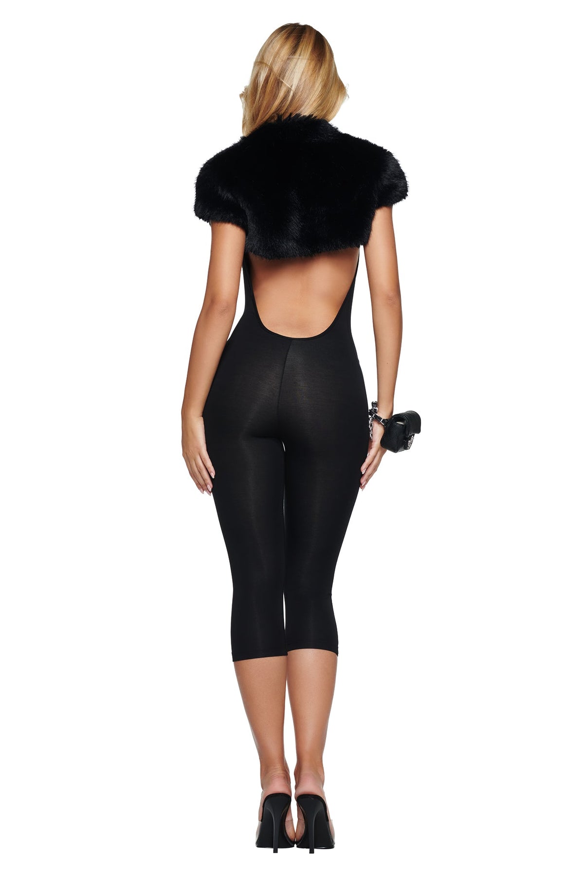 A person viewed from behind wearing an ALBA FAUX FUR CAP SLEEVE BOLERO - BLACK over a backless black jumpsuit with cropped legs and black heeled sandals.