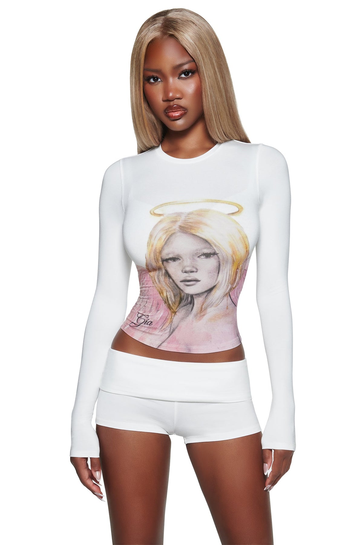A woman with long straight blonde hair wears a fitted white I.AM.GIA crop top and T-REX BLARE 2.0 SHORT - WHITE, standing against a white background.