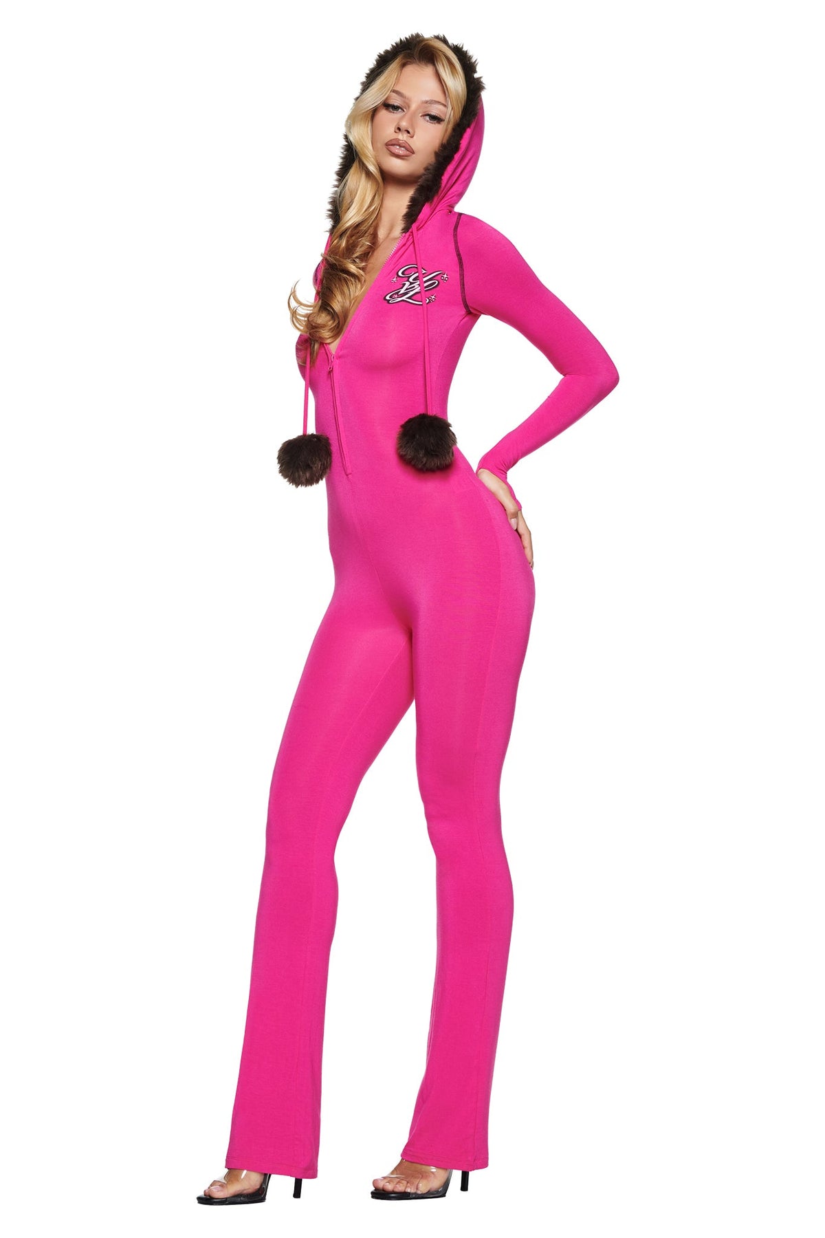 A person wears a form-fitting, hot pink YVL BLARE FUR LINED JUMPSUIT featuring a faux fur hooded design with pom-poms hanging from the front zipper.