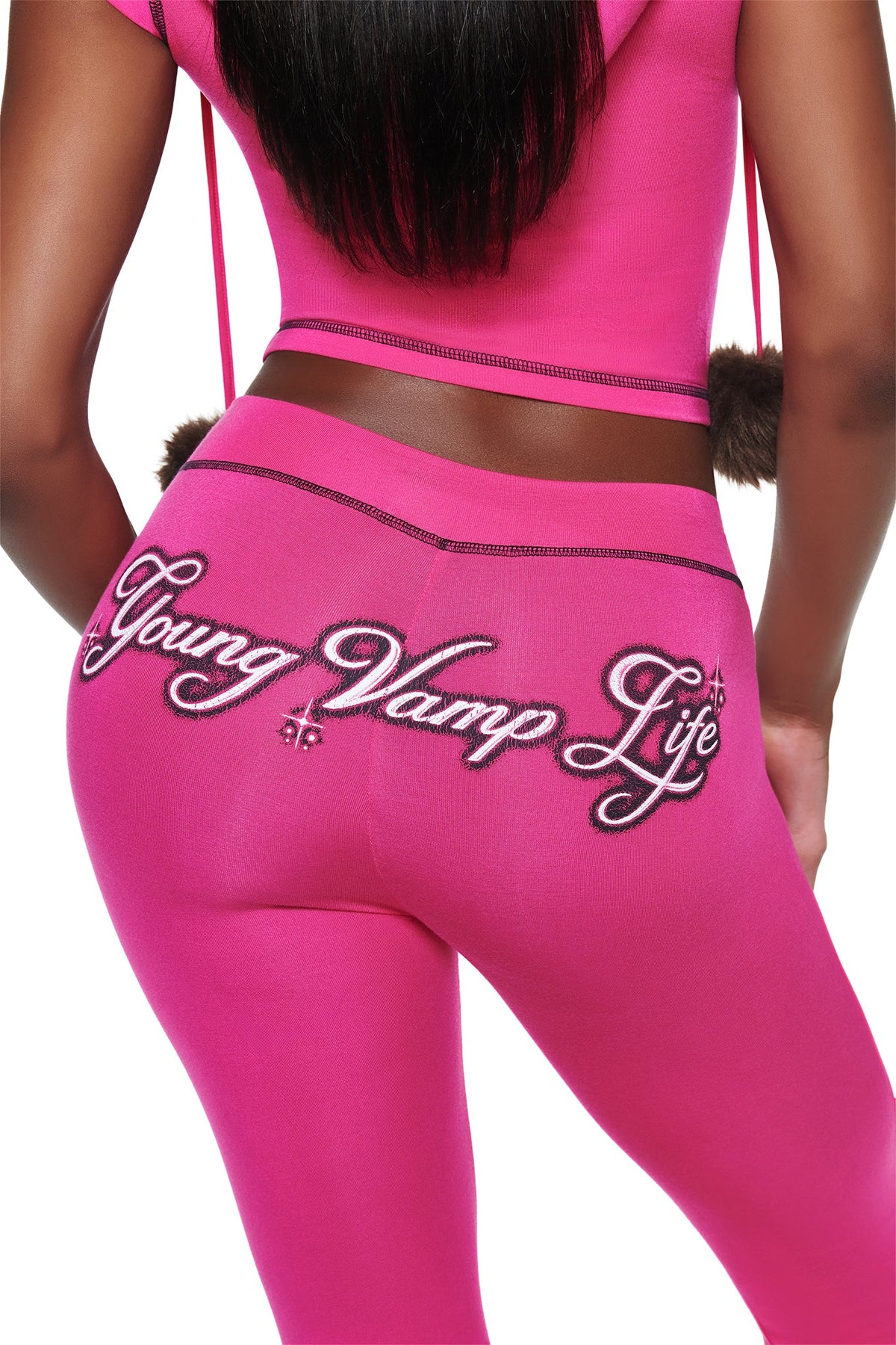 A person wearing hot pink YVL BLARE CAPRI - PINK pants with the words “Young Vamp Life” embroidered in script across the back.