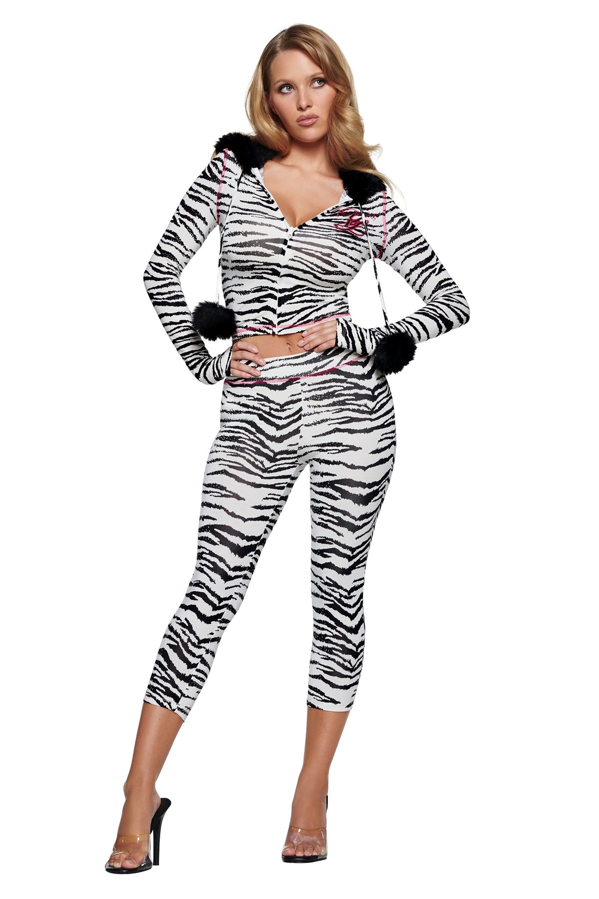 A woman wears a zebra-print zip-up hoodie with black faux fur trim and pom-poms, paired with matching zebra-print YVL BLARE CAPRI - ZEBRA pants.