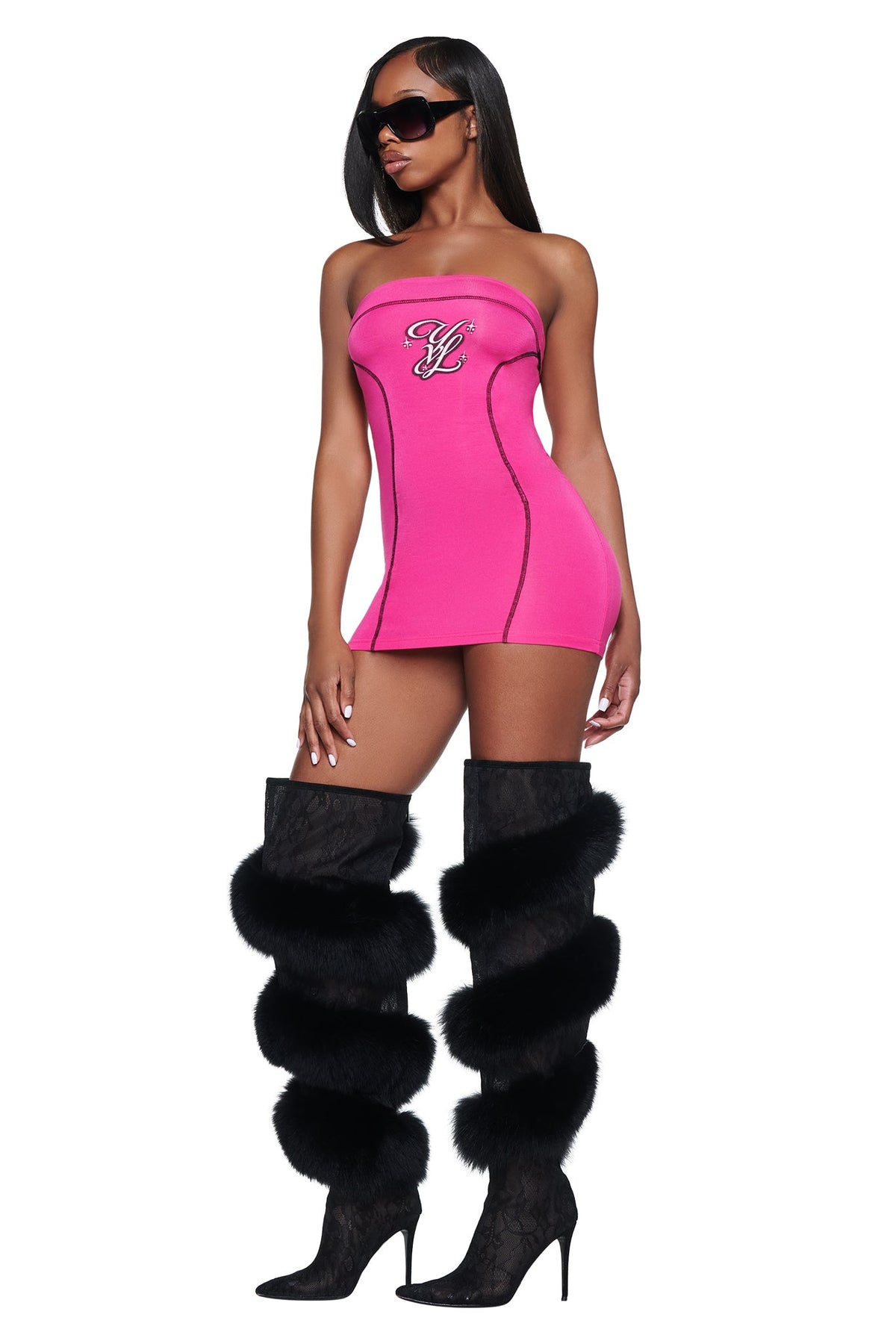 A person wearing a bright pink I.AM.GIA YVL BLARE TUBE MINI DRESS with a logo on the chest and black knee-high boots featuring horizontal fur trim.