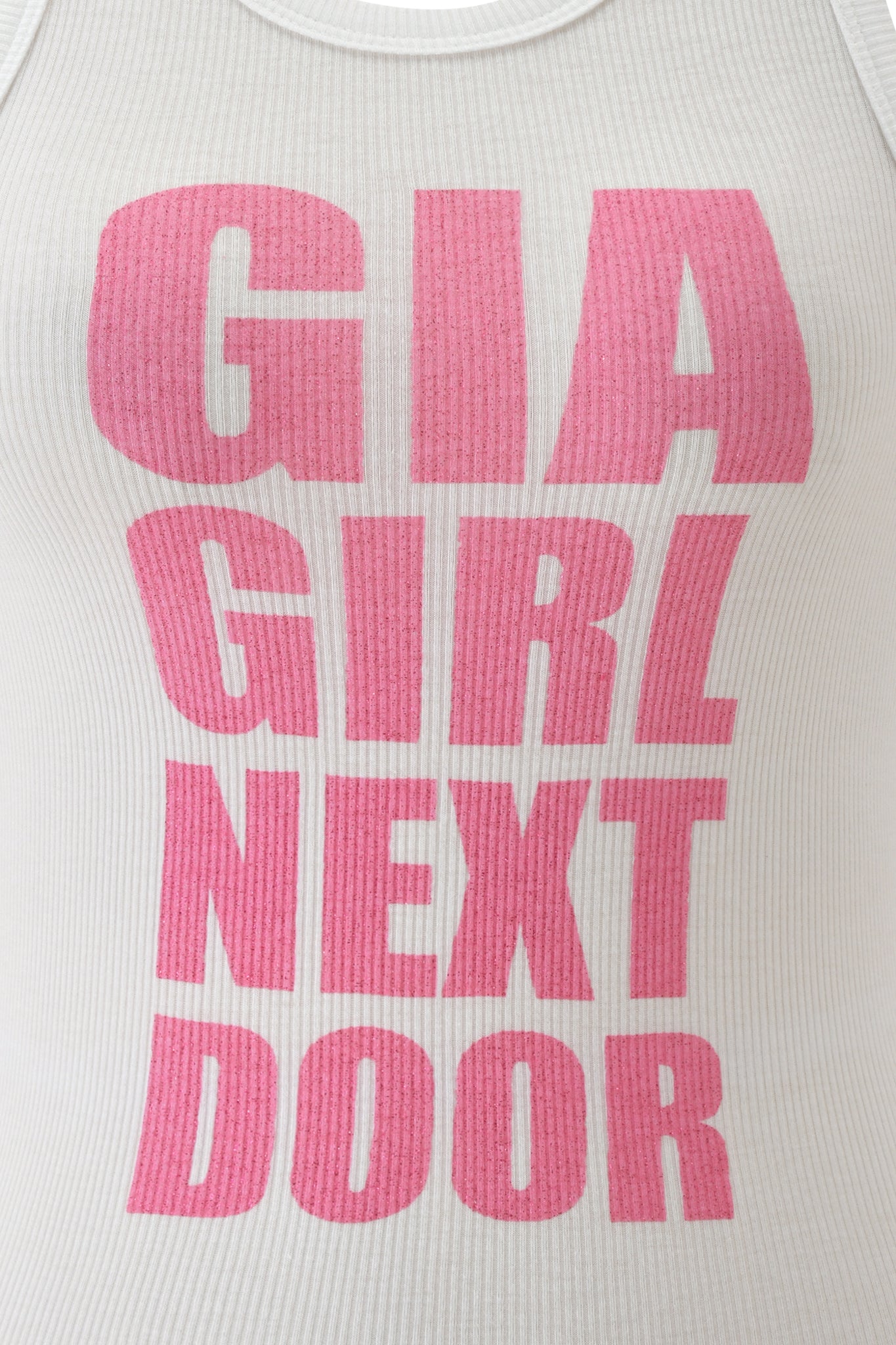 A close-up of the I.AM.GIA PENELOPE TANK—a white racer tank top featuring bold hot pink glitter letters that spell "GIRL NEXT DOOR.