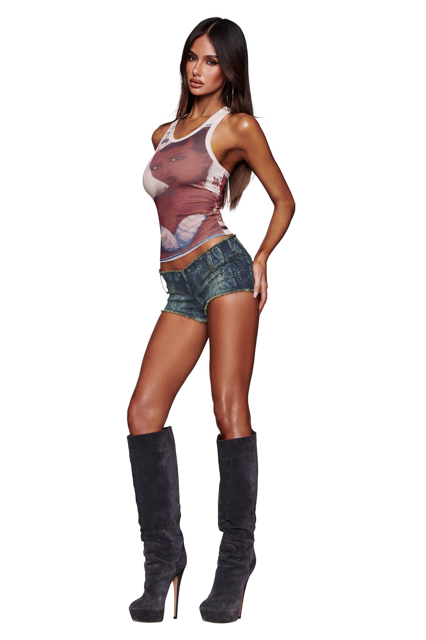 A woman poses against a white background wearing the I.AM.GIA T-REX PENELOPE TANK in white, paired with denim shorts and tall heeled boots.