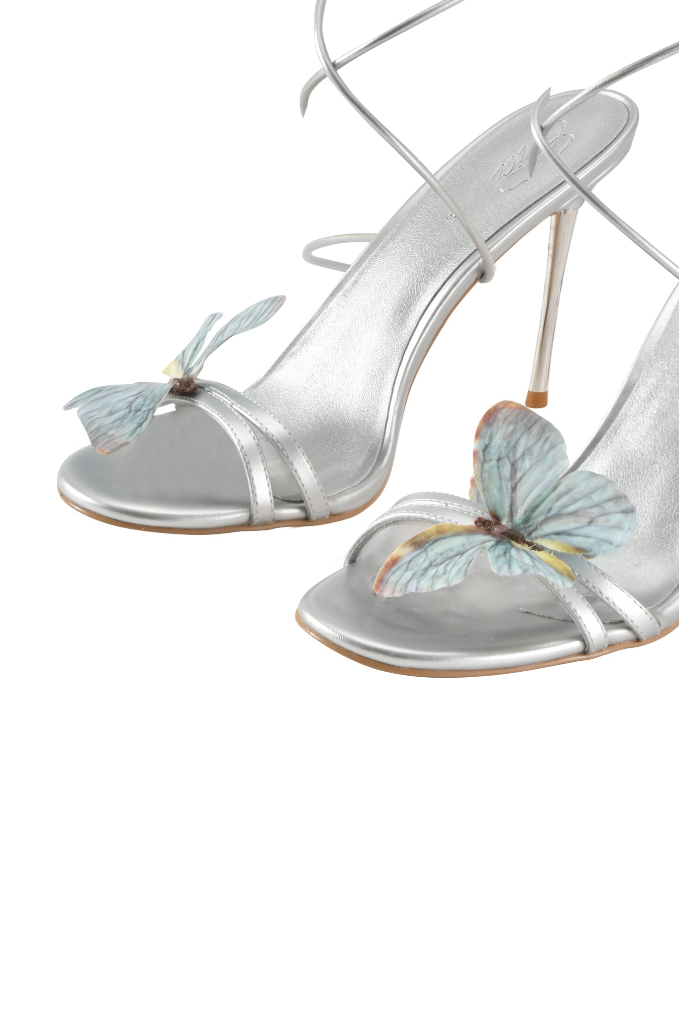 The SCARLETTE HEEL - SILVER by I.AM.GIA features a silver metallic open toe stiletto design with thin ankle straps and a light blue butterfly applique, offering an elegant, minimalist look.