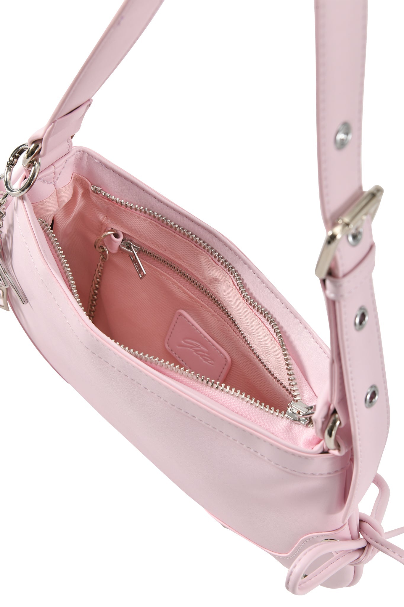 A close-up of the I.AM.GIA HAYLEY BAG in baby pink shows silver hardware, faux leather, a zippered pocket, an interior leather patch, and an adjustable shoulder strap on both sides.
