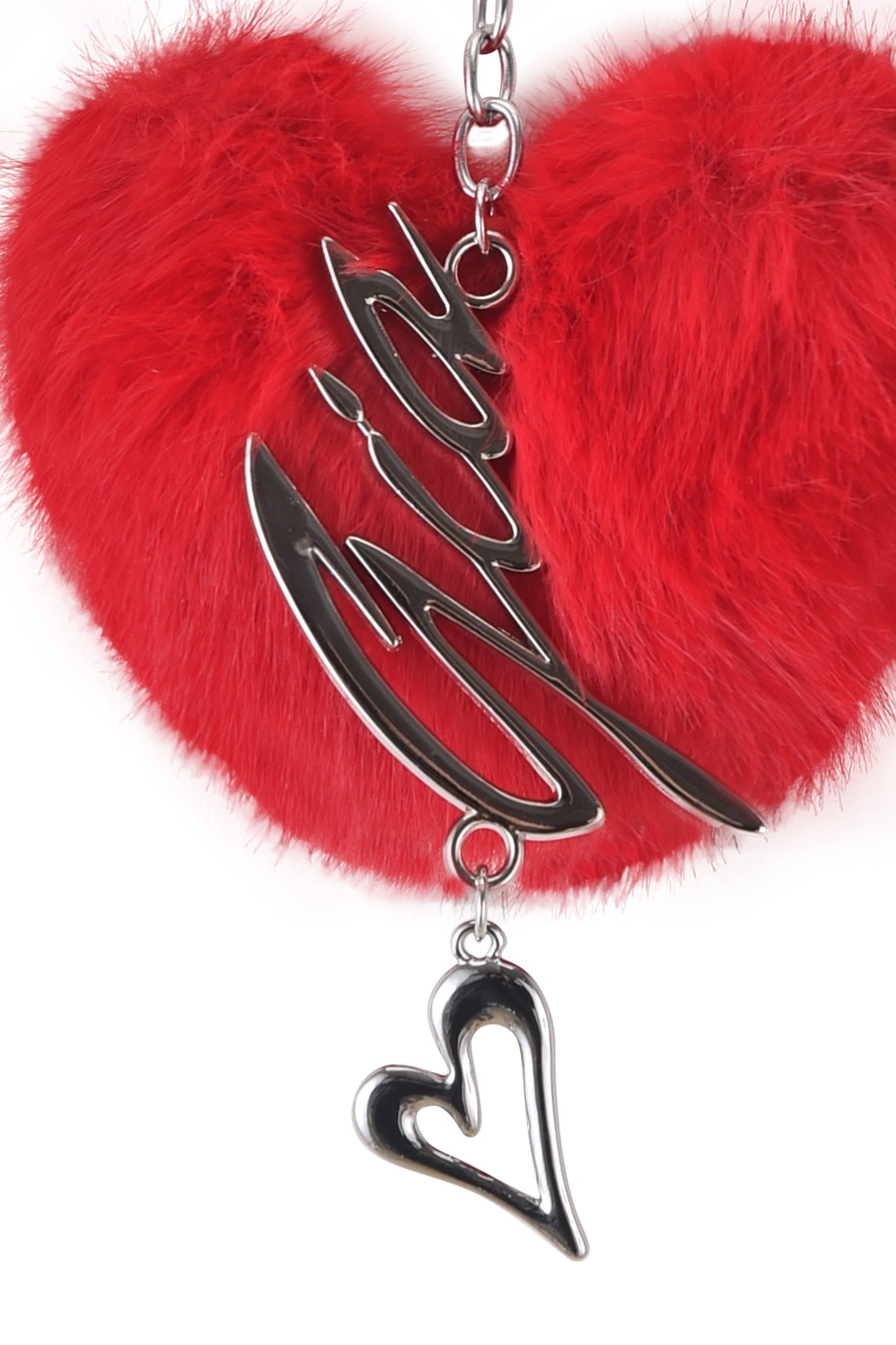 The VALENTINA KEYCHAIN by I.AM.GIA is a heart-shaped red faux fur keychain with a metallic chain, featuring a script-like word charm and small heart charm against a plain white background.