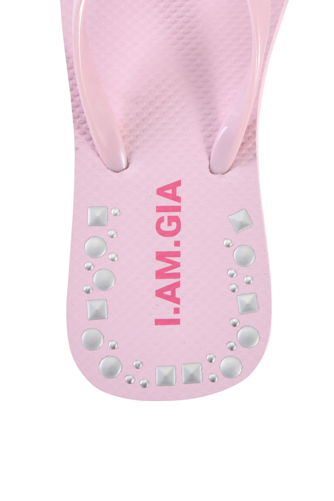 A close-up of the INKA STUDDED FLIP FLOP by I.AM.GIA in baby pink, featuring bold pink branding and silver studs with square embellishments arranged near the heel.