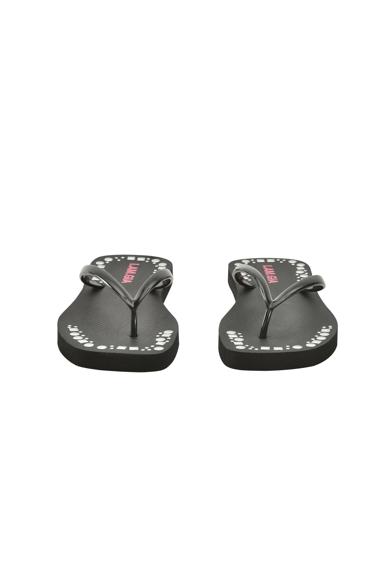 The INKA STUDDED FLIP FLOP by I.AM.GIA features black straps, white dotted edge patterns, pink text on ultra-soft foam footbeds, and is shown from the front against a white background.