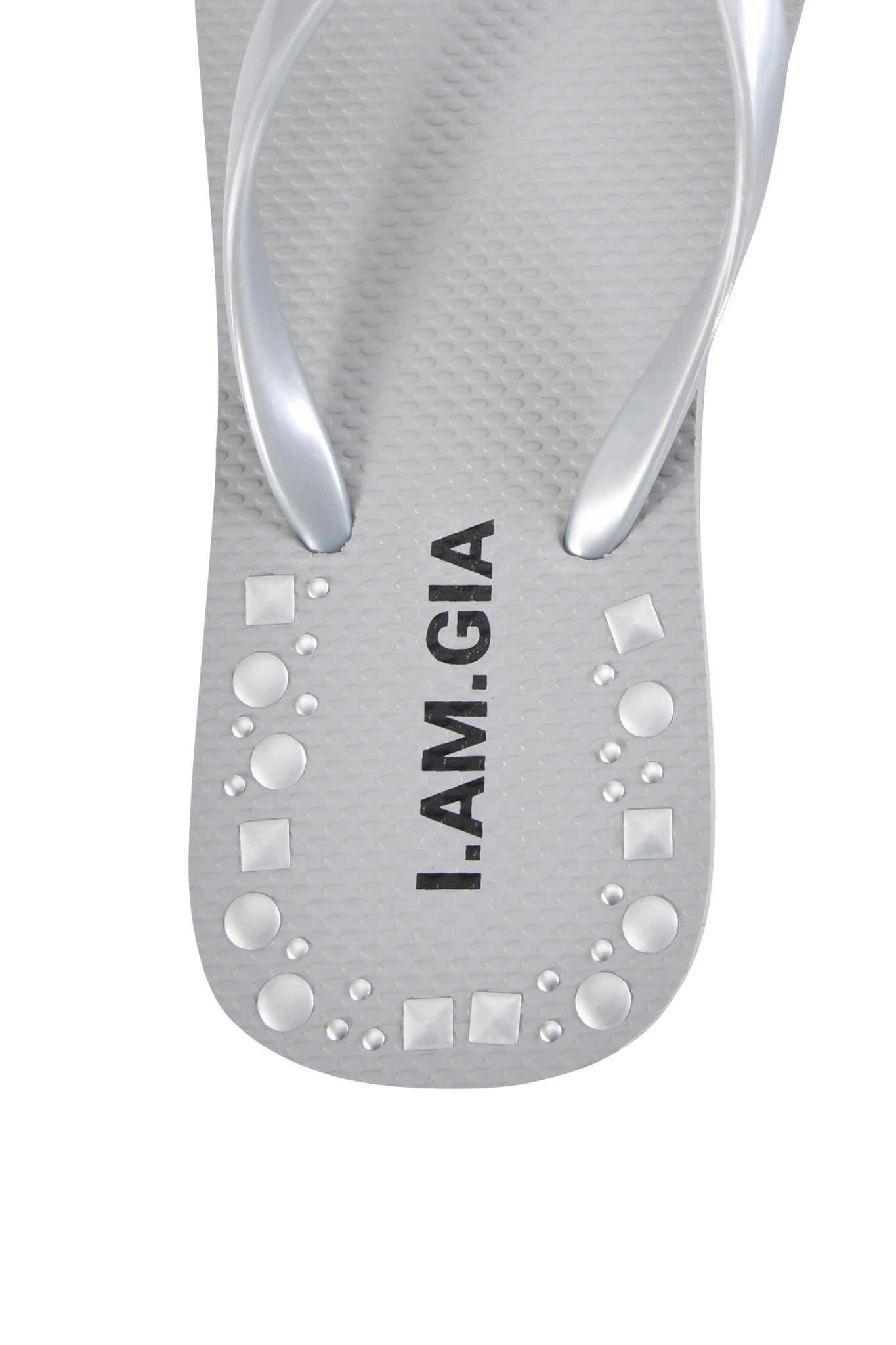 A close-up of the INKA STUDDED FLIP FLOP - SILVER by I.AM.GIA, featuring gray footbeds, silver studded straps, "I.AM.GIA" printed vertically, and small silver studs near the toe for added style and comfort.