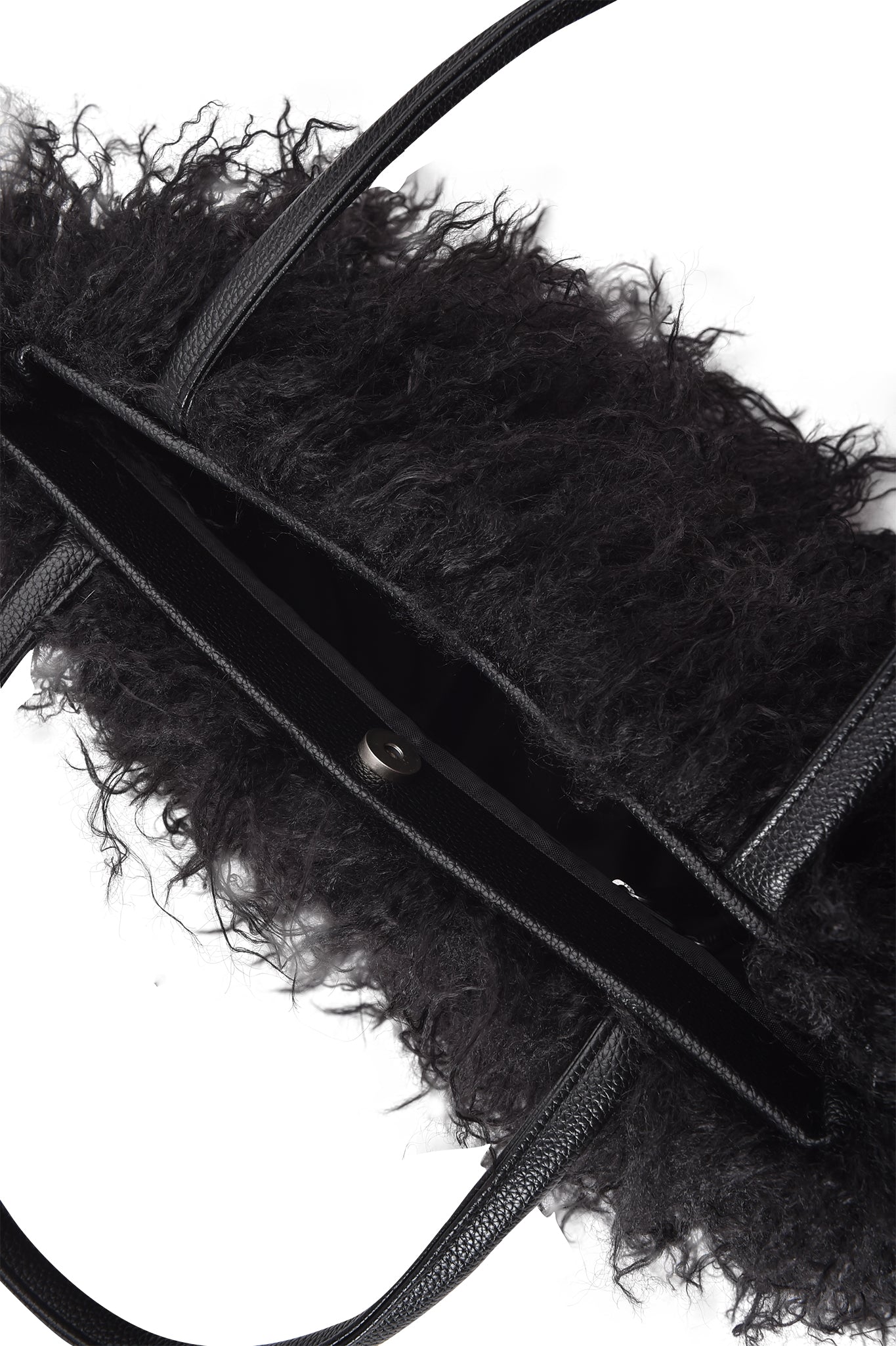 The I.AM.GIA PIXI FAUX FUR BAG - BLACK is shown from above, highlighting its textured, fluffy exterior, faux leather handles, and a partially open main compartment with a button closure against a white background.