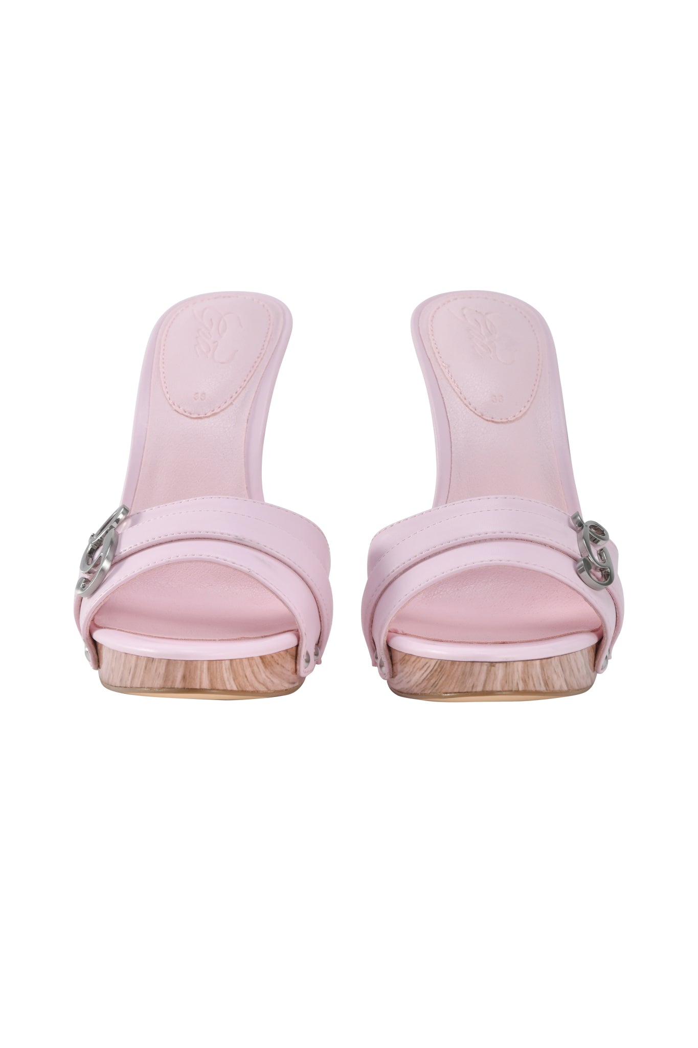 The NICKY HEEL - STUDDED BABY PINK by I.AM.GIA features light pink faux leather, open toes, wooden soles, and side straps with silver buckle accents, shown from the front.