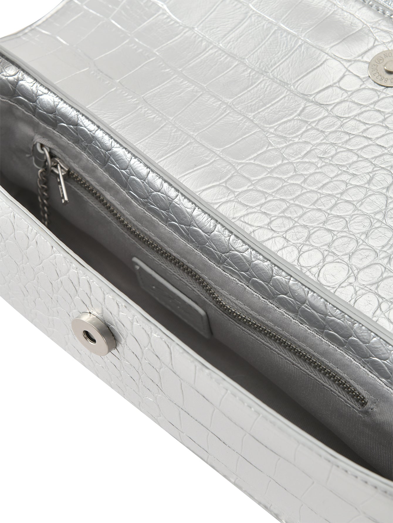 Close-up of the MILA METALLIC BAG in silver metallic by I.AM.GIA, featuring faux crocodile texture, a magnetic snap closure, GIA branding, and an interior zippered pocket with metal zipper pull.