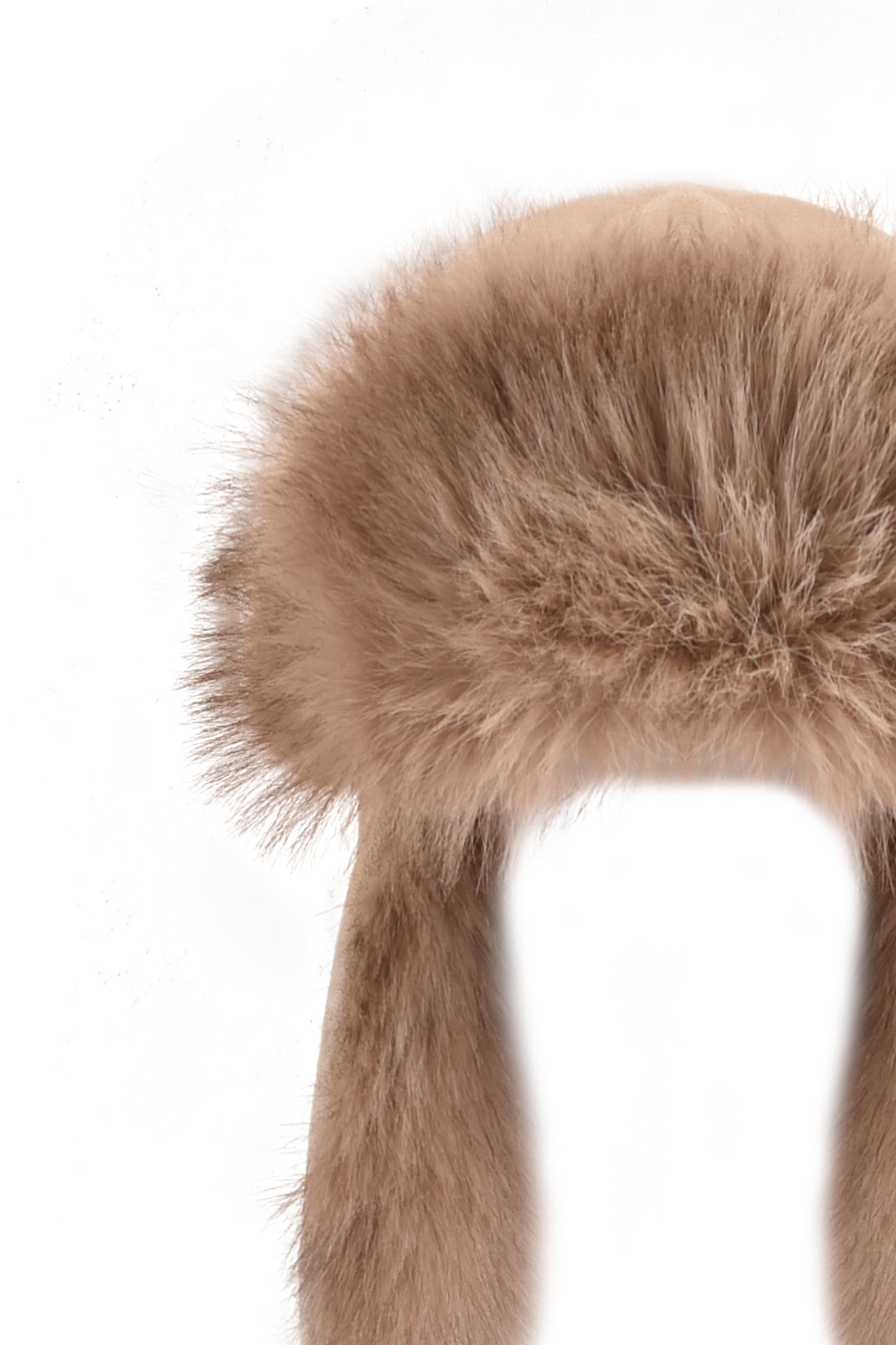 A close-up of the I.AM.GIA GENA FAUX FUR TRAPPER HAT in tan suede, featuring a fluffy, reversible design with two long ear flaps, photographed against a white background.